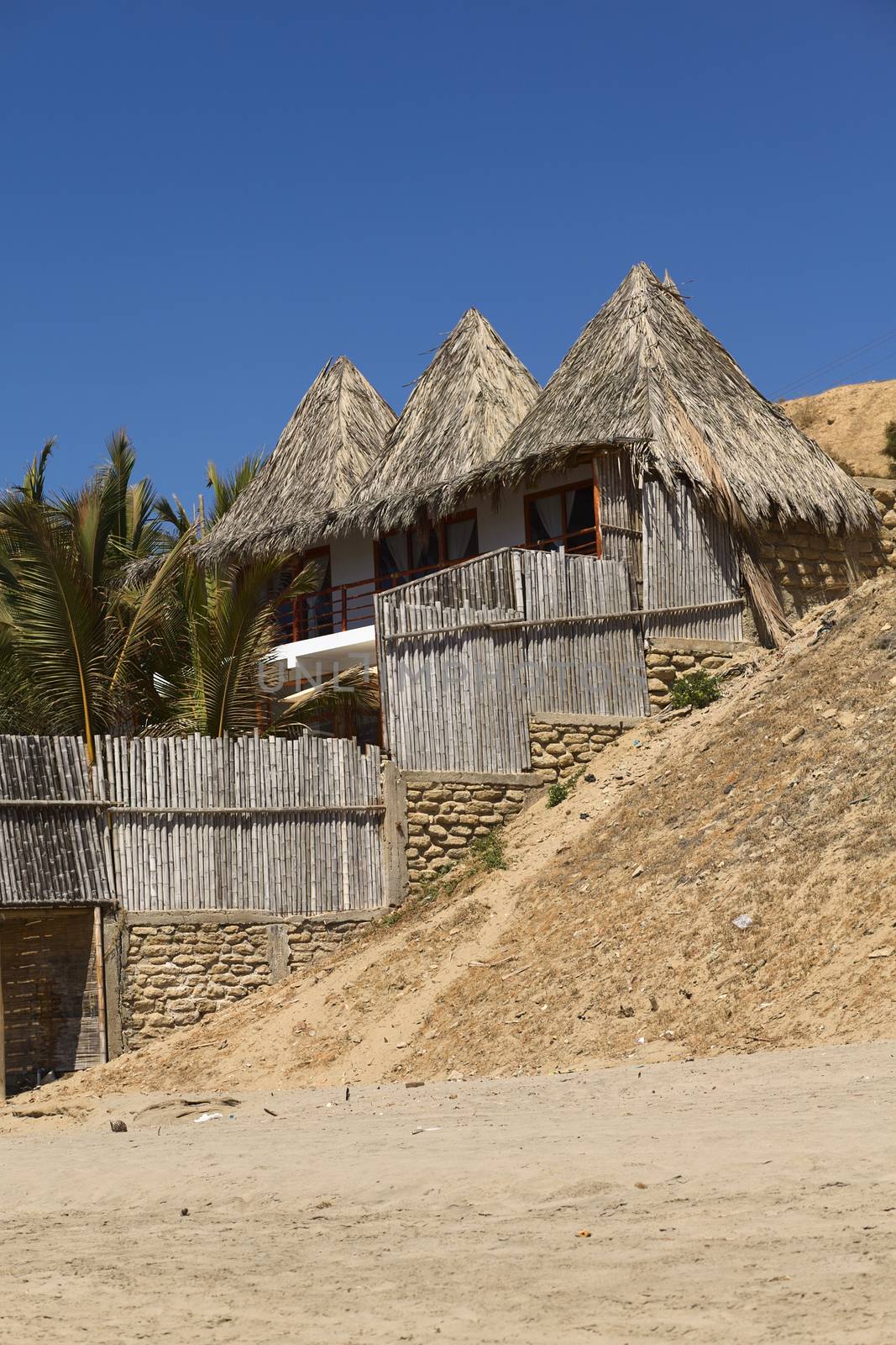 MANCORA, PERU - AUGUST 17, 2013: Thatched roof accomodation with palm trees along the sandy beach on August 17, 2013 in Mancora, Peru. Mancora is one of the most popular beach towns of Peru. 