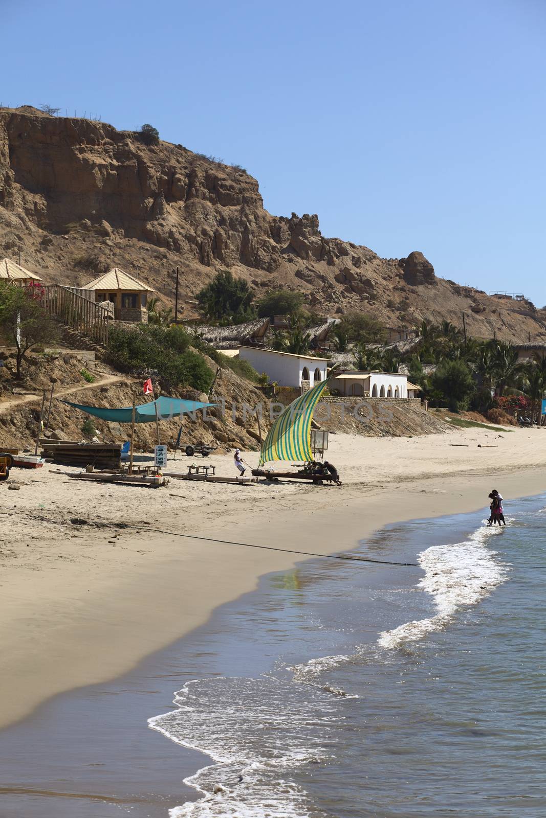 MANCORA, PERU - AUGUST 17, 2013: Unidentified people walking and others pulling a raft with sail on the beach on August 17, 2013 in Mancora, Peru. Mancora is one of the most popular beach towns in Peru. 