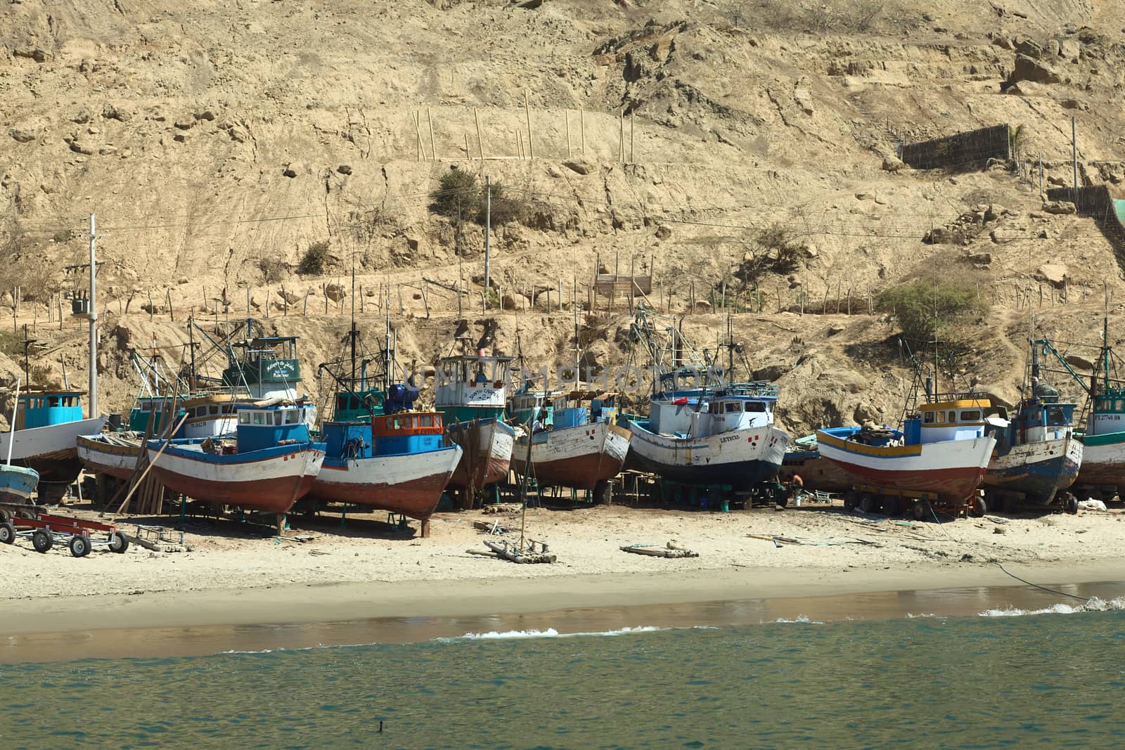 MANCORA, PERU - AUGUST 17, 2013: Old wooden fishing boats and some rafts on the sandy beach on August 17, 2013 in Mancora, Peru. Mancora is a small town in Northern Peru living from fishing and tourism.
