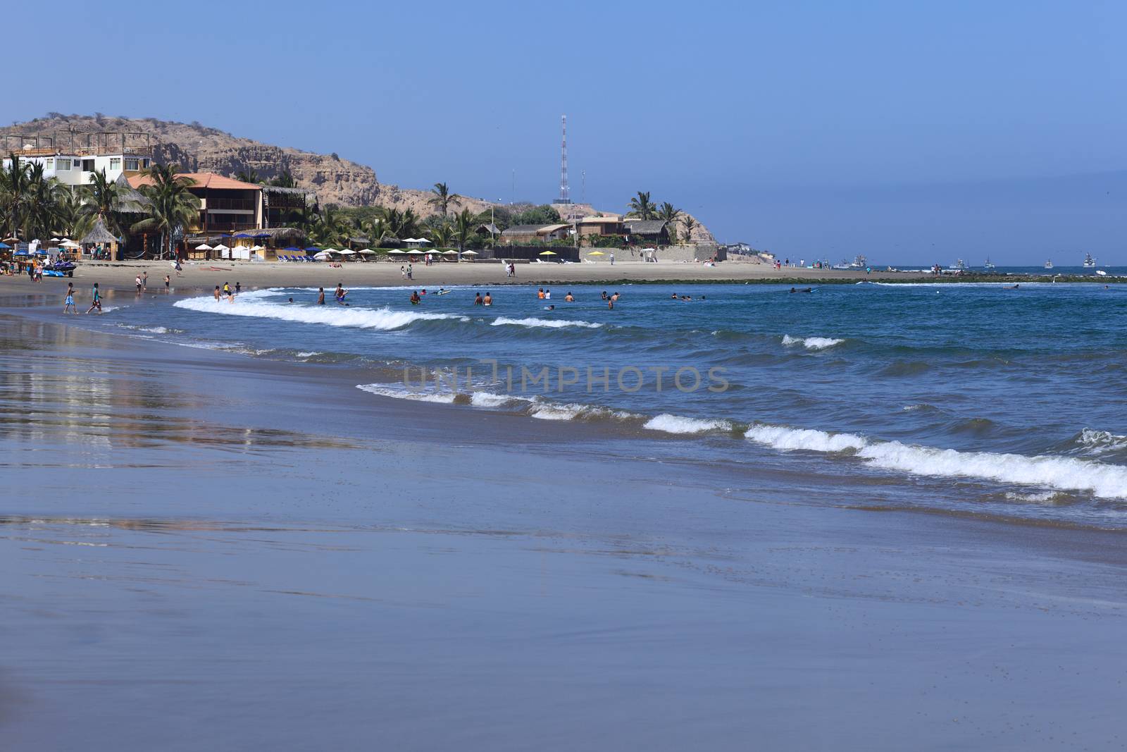 MANCORA, PERU - OCTOBER 4, 2013: Unidentified people on the beach and in the water on a sunny day on October 4, 2013 in Mancora, Peru. Mancora is a popular beach town in Northern Peru.  