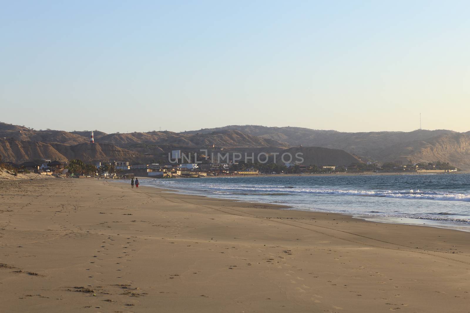 MANCORA, PERU - AUGUST 18, 2013: Unidentified people on the sandy beach with view onto the tourist part of town along the coast on August 18, 2013 in Mancora, Peru. The small town of Mancora is known for its sandy beaches and is popular with Peruvian and foreign tourists. 