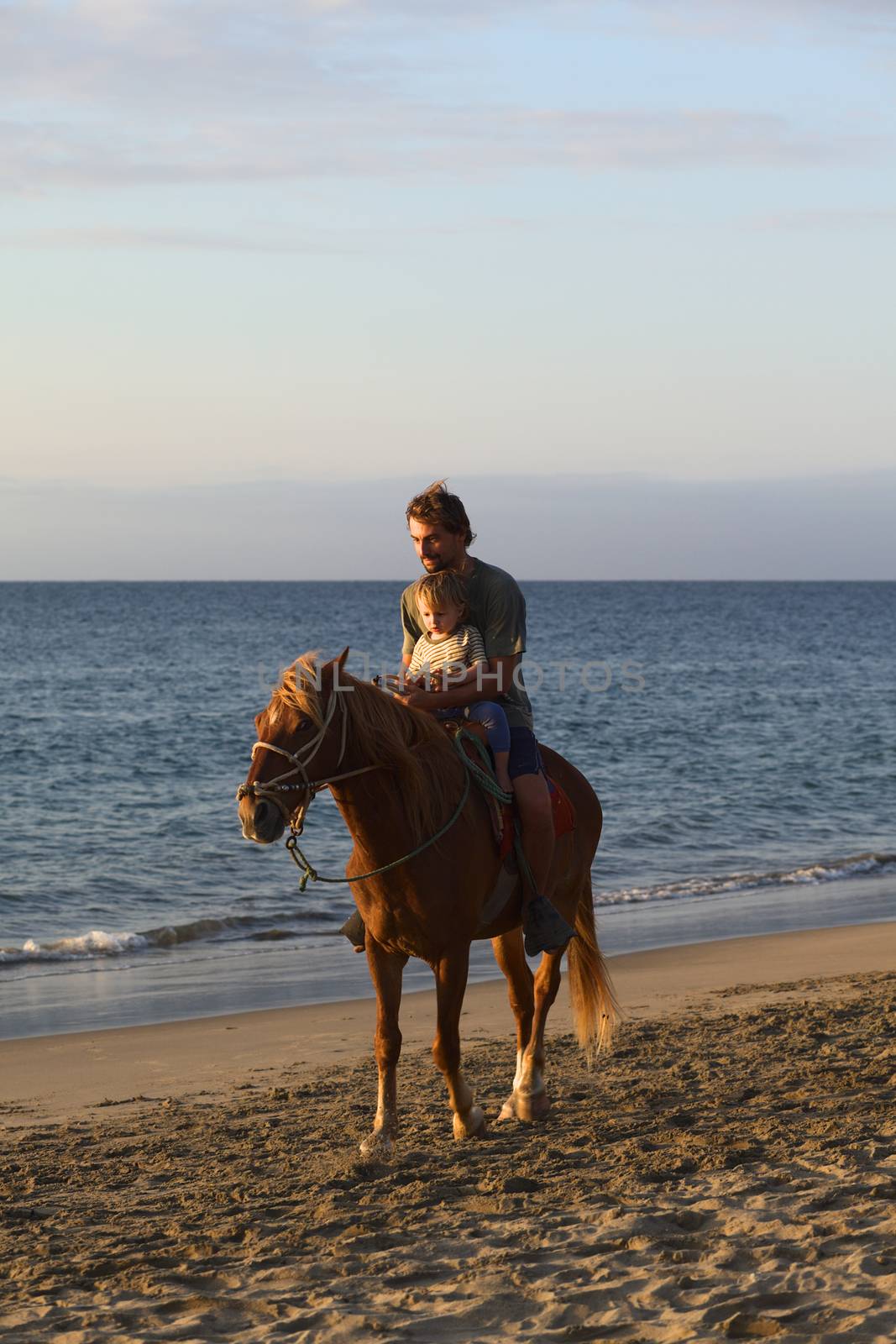 MANCORA, PERU - AUGUST 20, 2013: Unidentified young man and child on horseback on the beach on August 20, 2013 in Mancora, Peru. Mancora is a popular beach town in Northern Peru both for Peruvian and foreign tourists