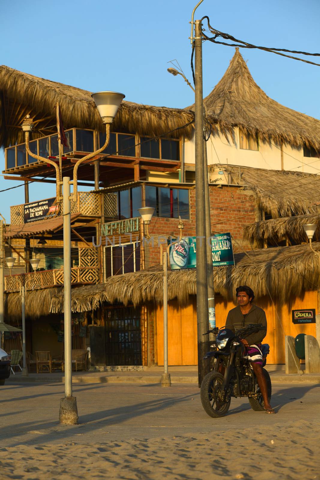 MANCORA, PERU - AUGUST 20, 2013: Unidentified young man on motorbike watching the setting sun and the beach on August 20, 2013 in Mancora, Peru. The small town of Mancora in Northern Peru is known for its sandy beaches and is popular with Peruvian and foreign tourists.