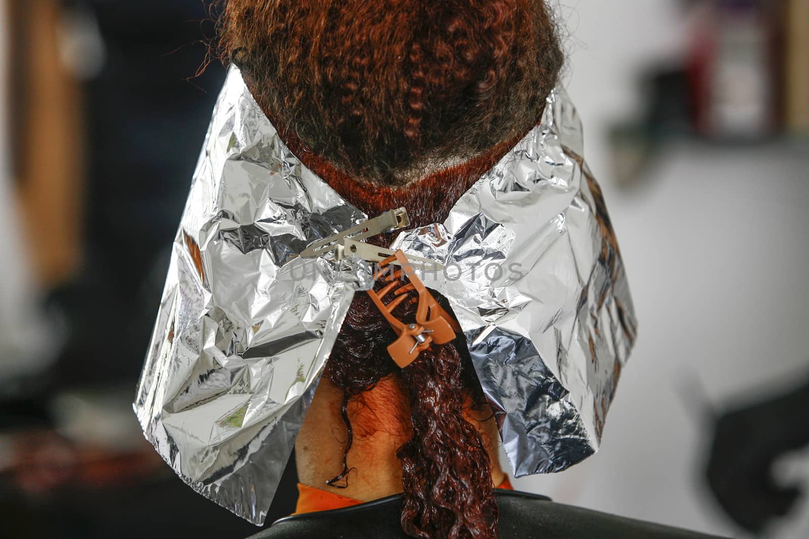Close-up of the head of a woman in the process of getting her hair dyed by her beautician