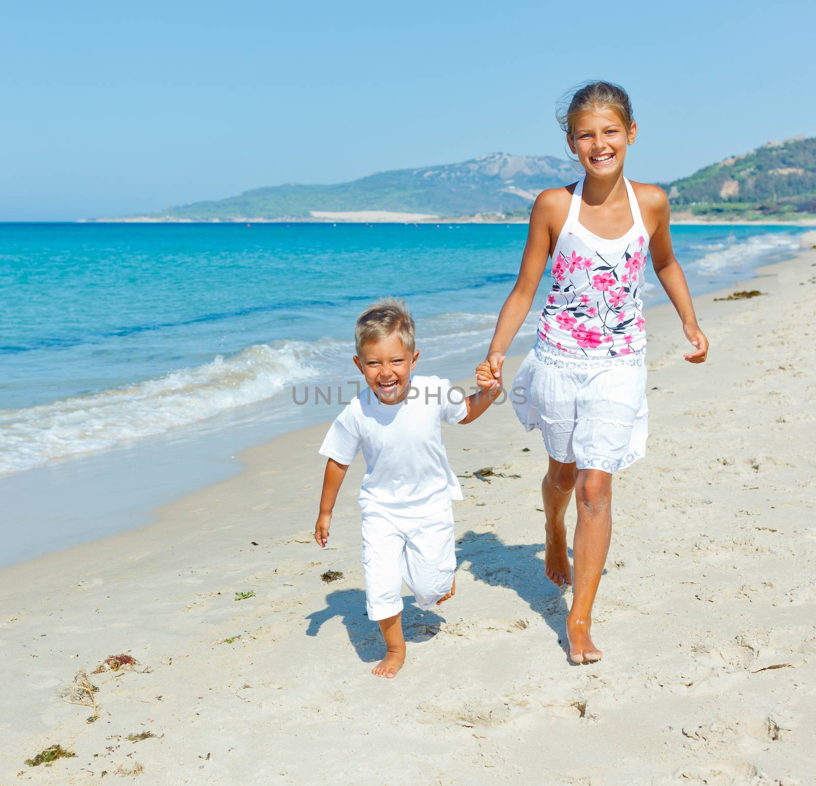 Adorable happy boy and girl runs along beach vacation