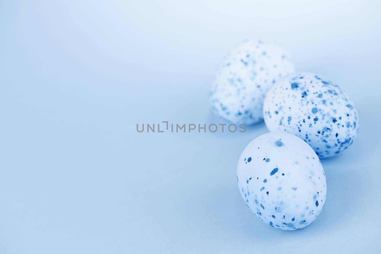 Three pale blue speckled painted easter eggs with copy space