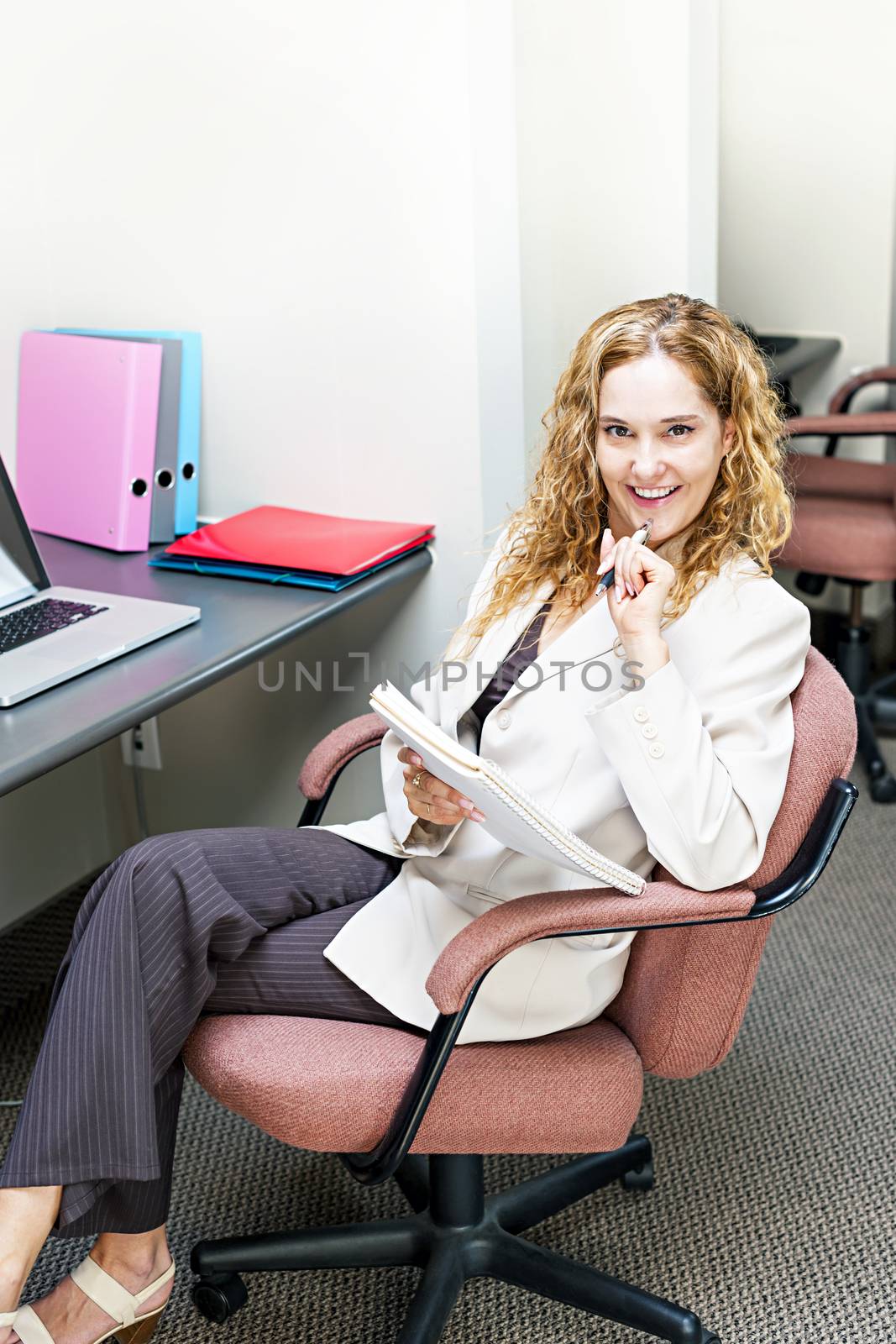 Smiling businesswoman thinking of ideas in office workstation