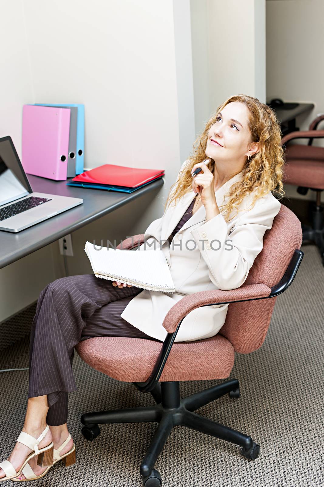 Businesswoman thinking of ideas in office workstation looking up