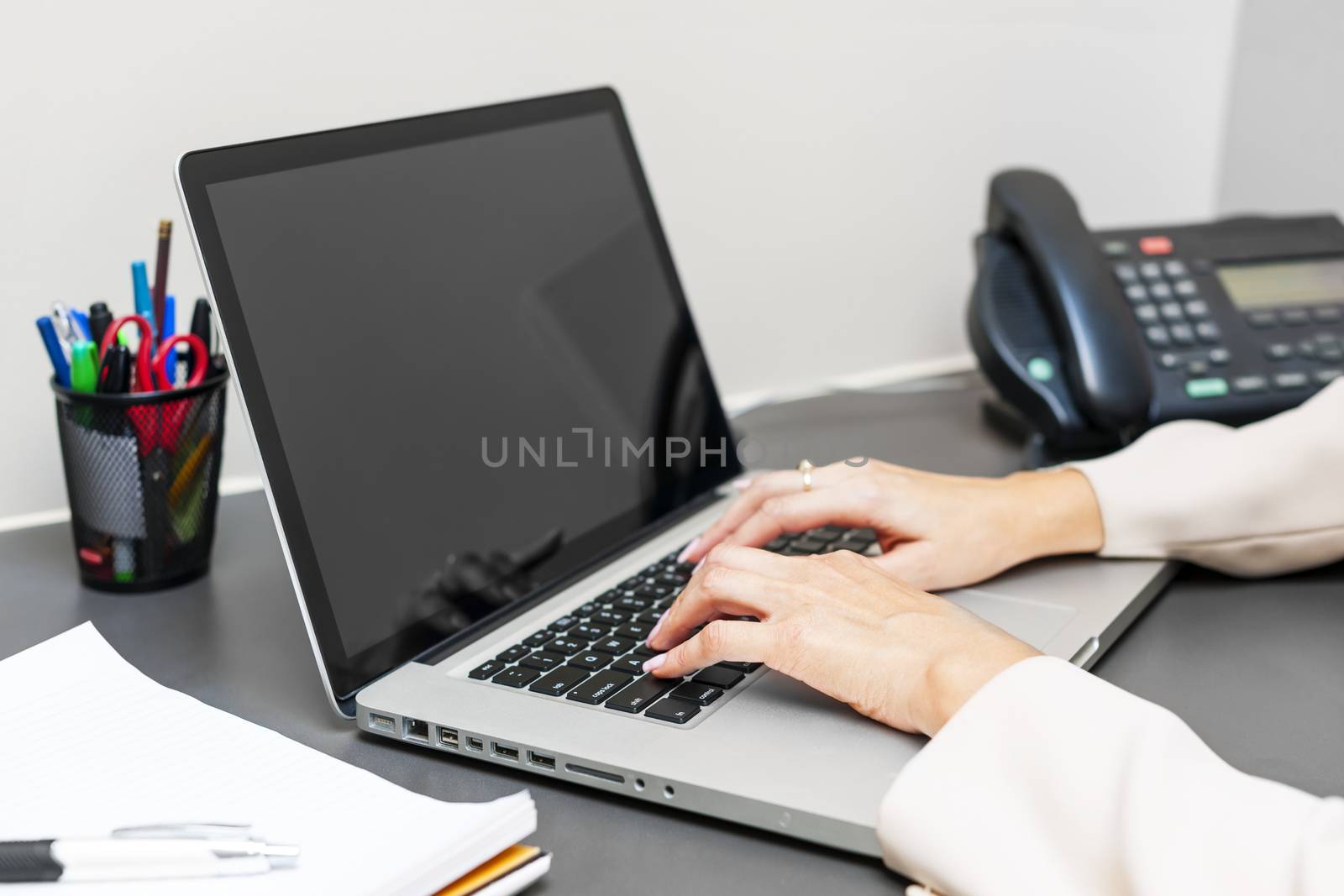 Female hands typing on laptop keyboard at office desk