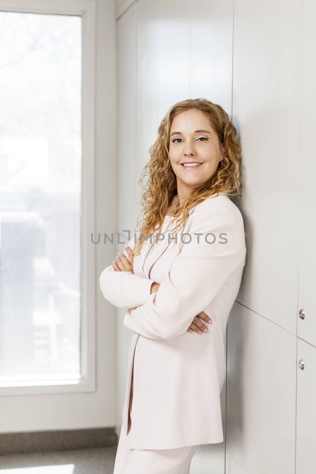 Proud businesswoman standing in hallway by elenathewise