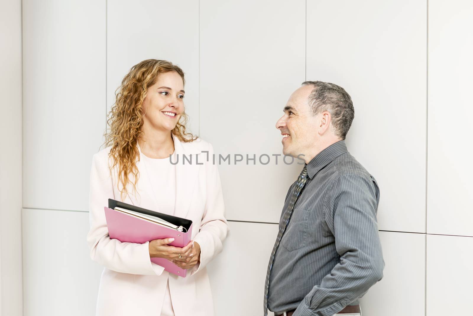 Man and woman discussing work in business office hallway