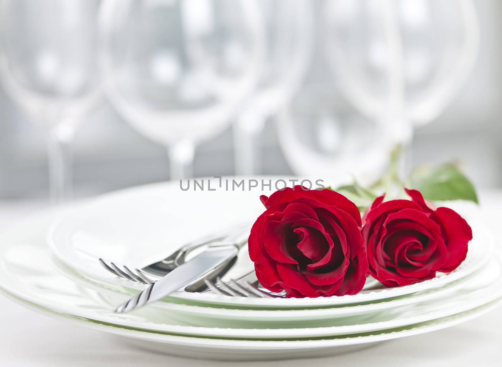 Romantic restaurant table setting for two with roses plates and cutlery