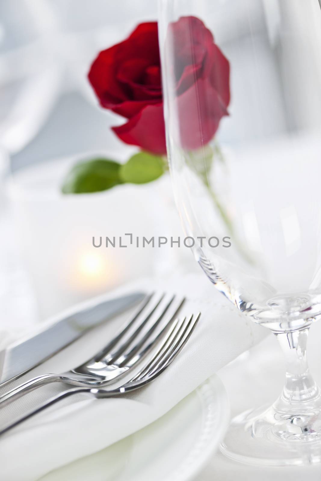 Romantic restaurant table setting with rose candle plates and cutlery