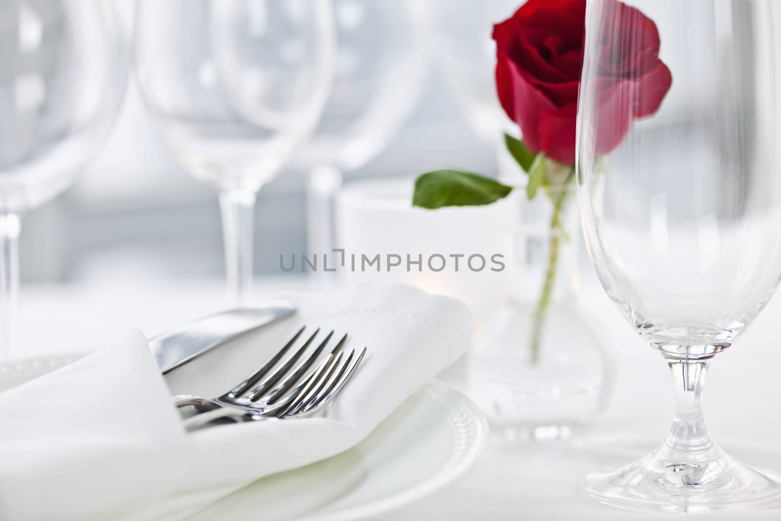 Romantic restaurant table setting with rose candle plates and cutlery