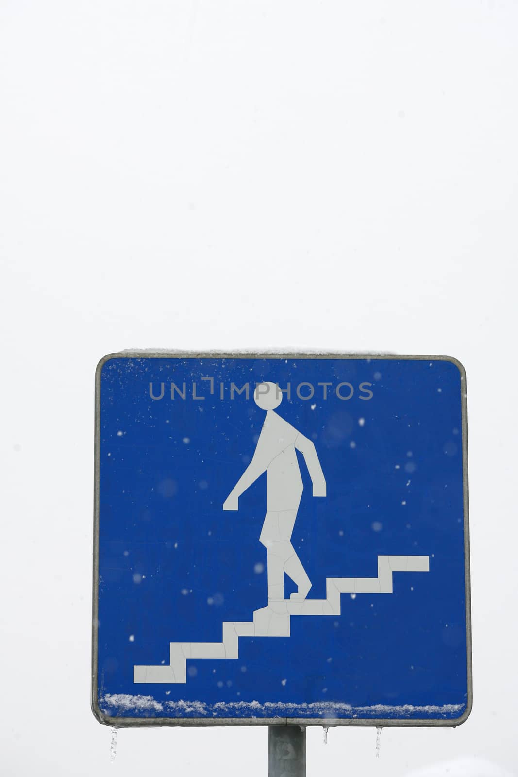 Road sign of a pedestrian underpass in winter with ice