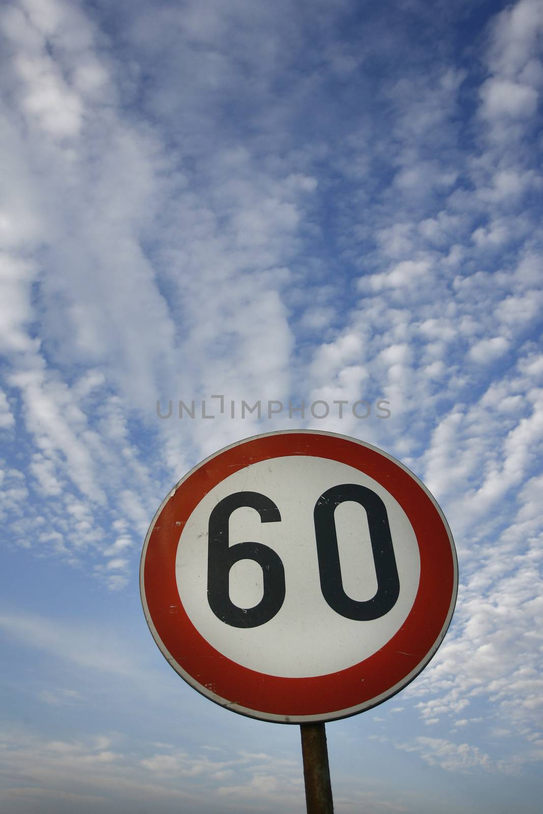 road sign speed limit sixty under cloudy blue sky