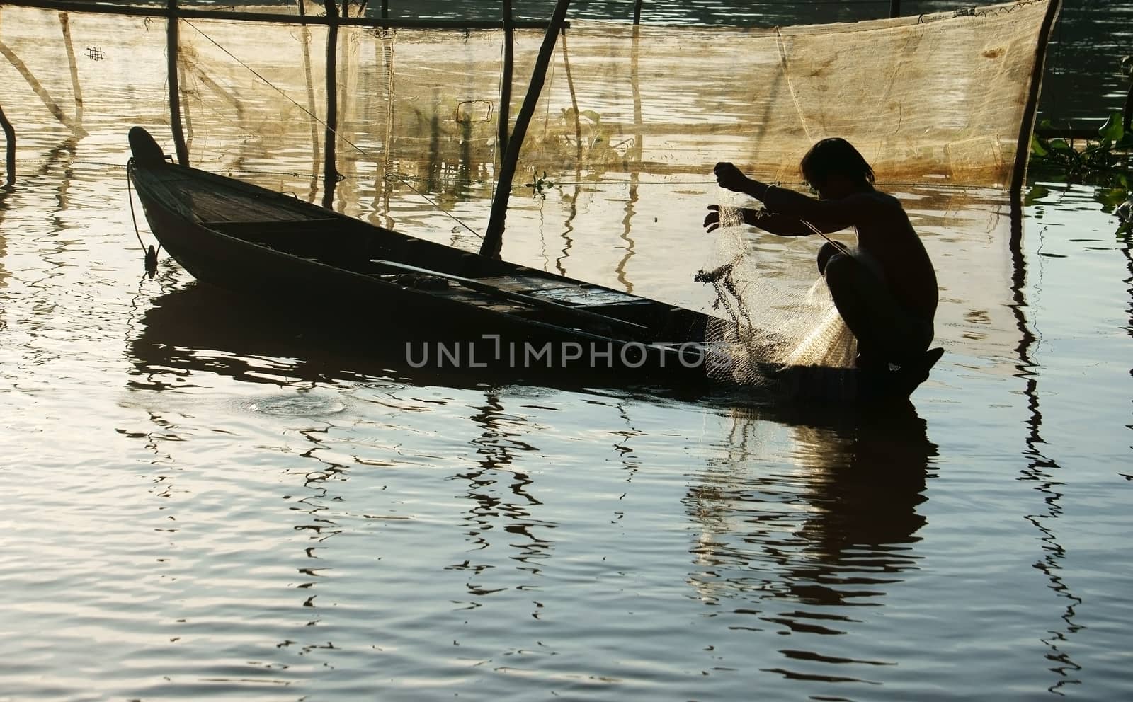 silhouette  's fisherman sitting on row boat, pick up the net, repair for fishing to catch fish on river at morning in flood season 