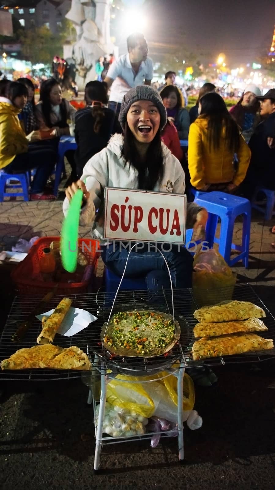 DA LAT, VIET NAM- DEC 29: Friendly, joyful, funny of Vietnamese street food vendor at night outdoor market  grill baked girdle cake- one of eating street, in Dalat, Vietnam on Dec 29,2013