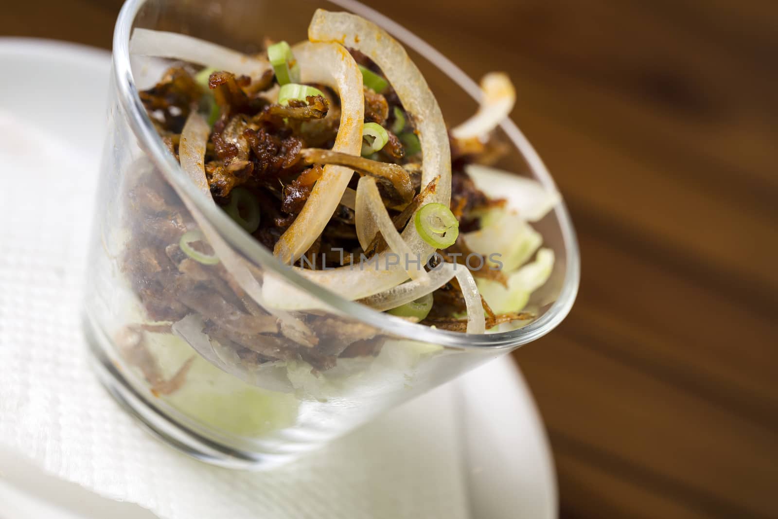 A glass of spicy anchovies snack ready to be served.