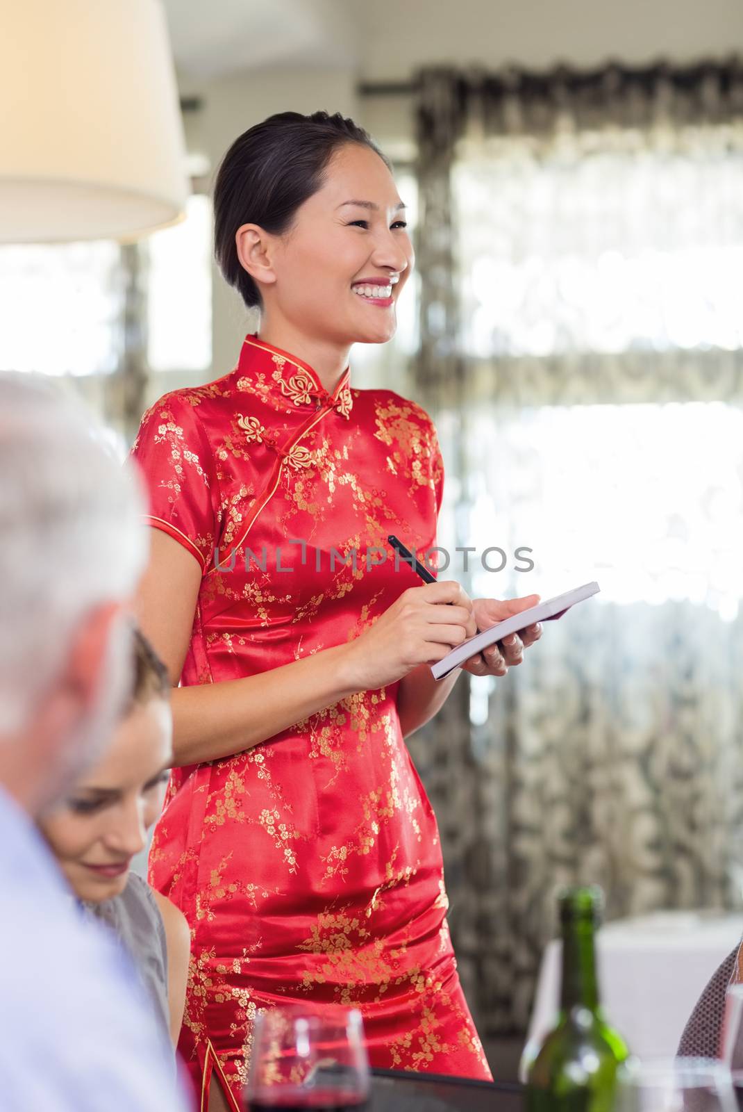 Portrait of a smiling waitress with people sitting at dining table in the restaurant