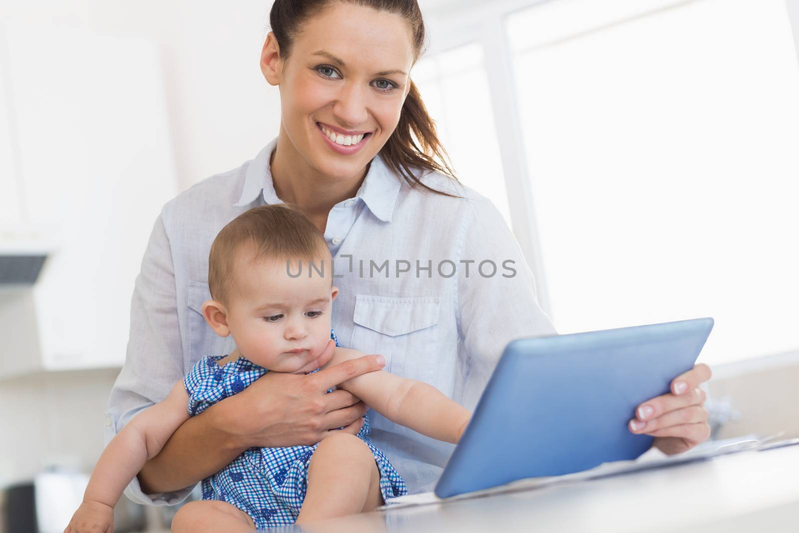 happy mother calculating finances while holding baby by Wavebreakmedia