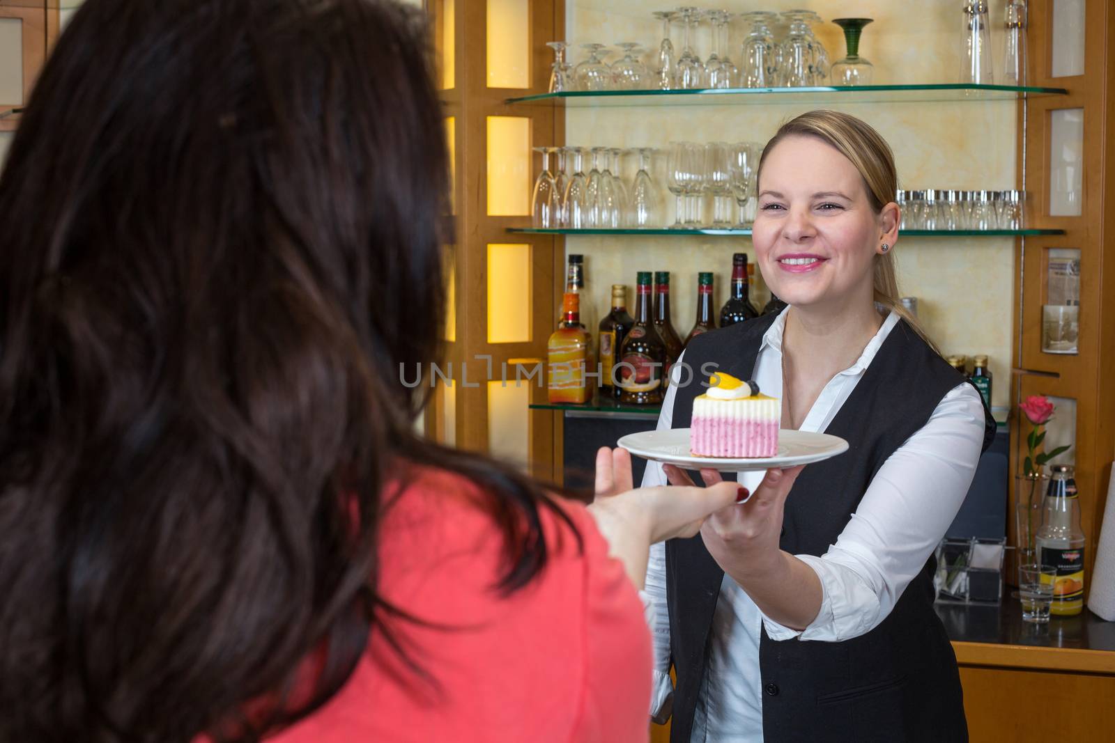 waitress gives piece of cake to client by ikonoklast_fotografie