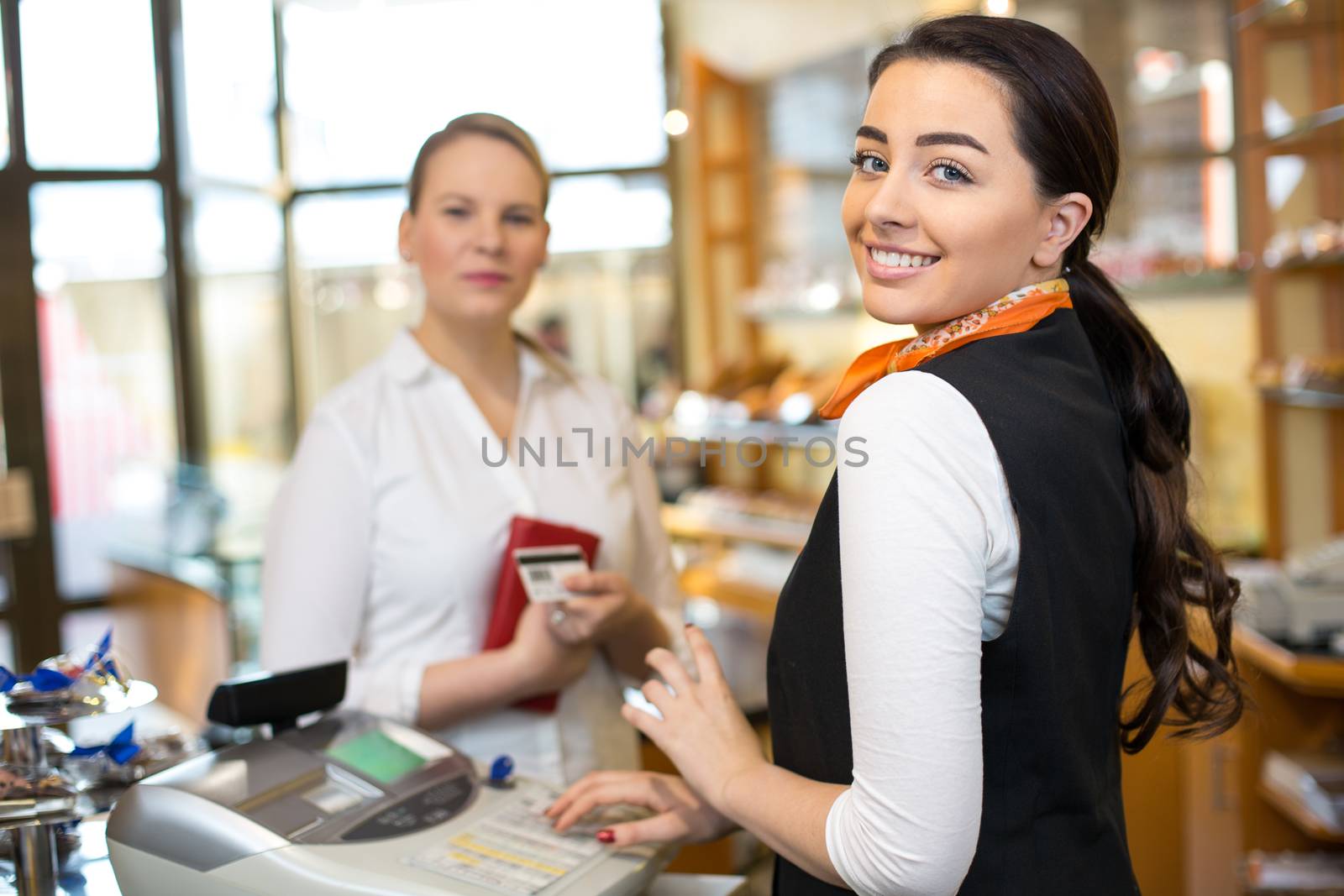 Client at shop paying at cash register by ikonoklast_fotografie