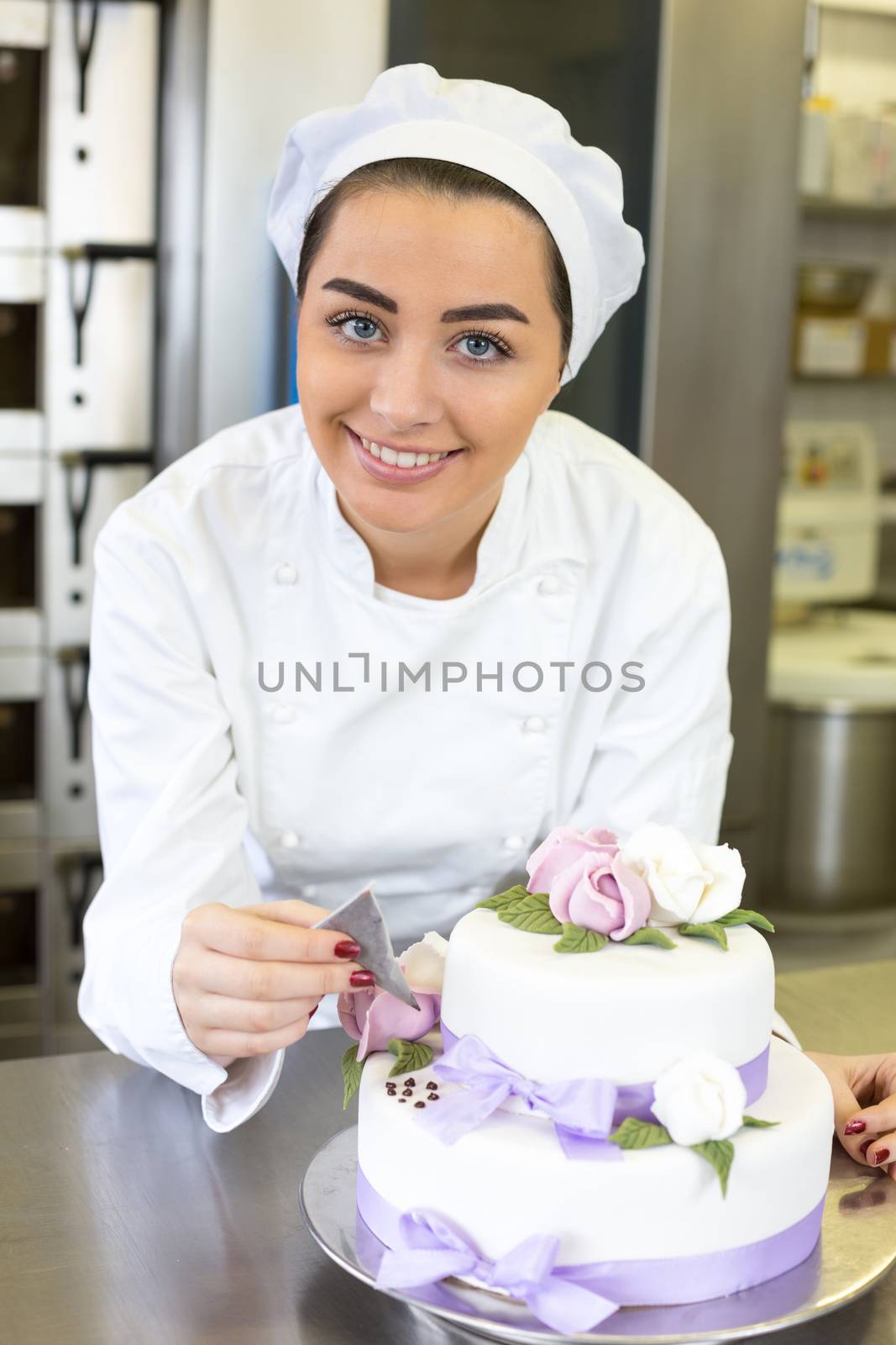 Baker or confectioner writes something on a cake with food colouring
