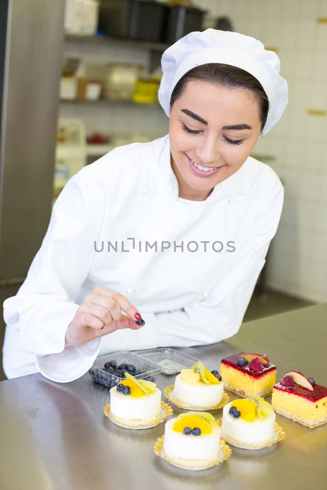 Confectioner preparing cakes at bakery or confectionery by ikonoklast_fotografie