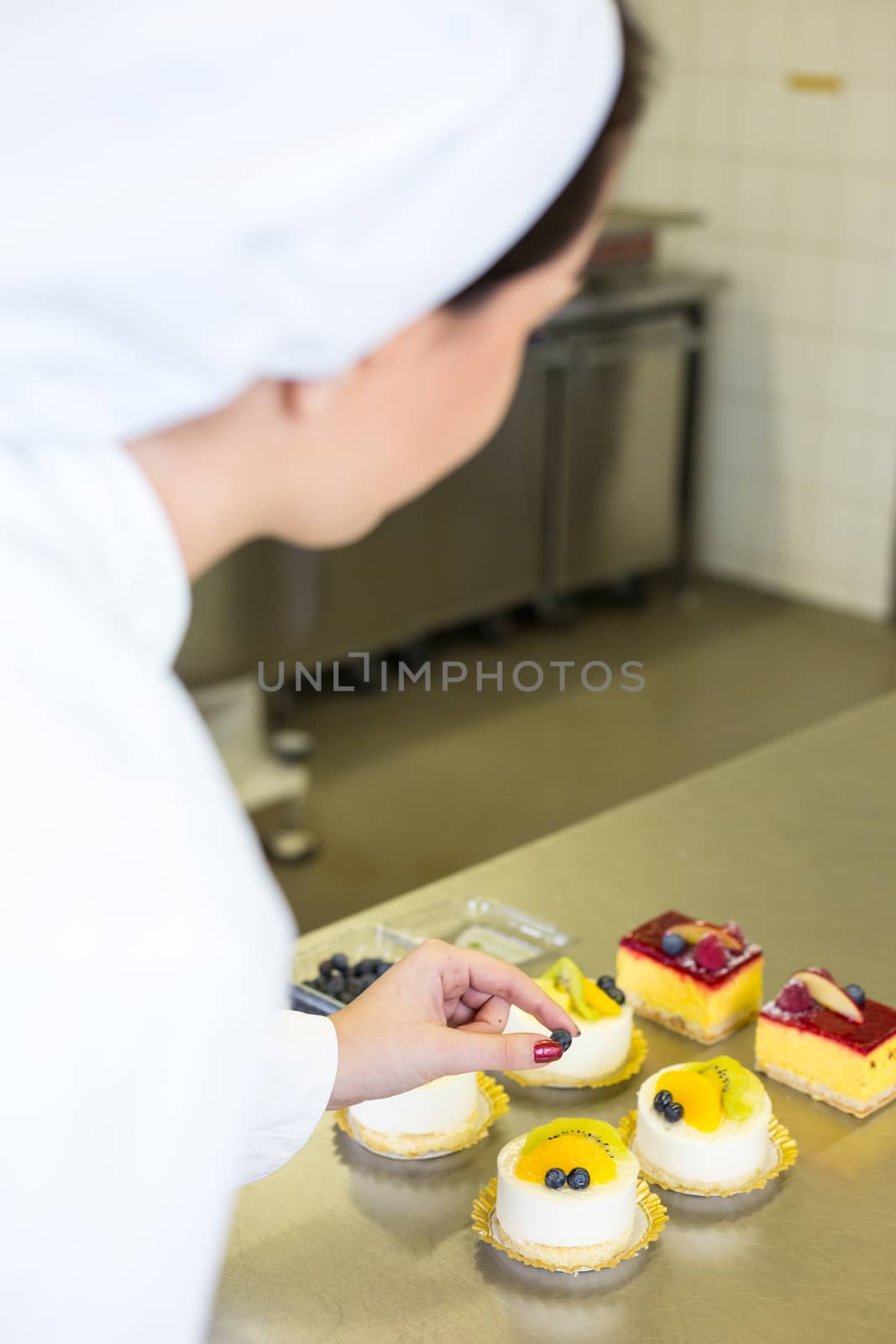 Confectioner preparing cakes at bakery or confectionery by ikonoklast_fotografie