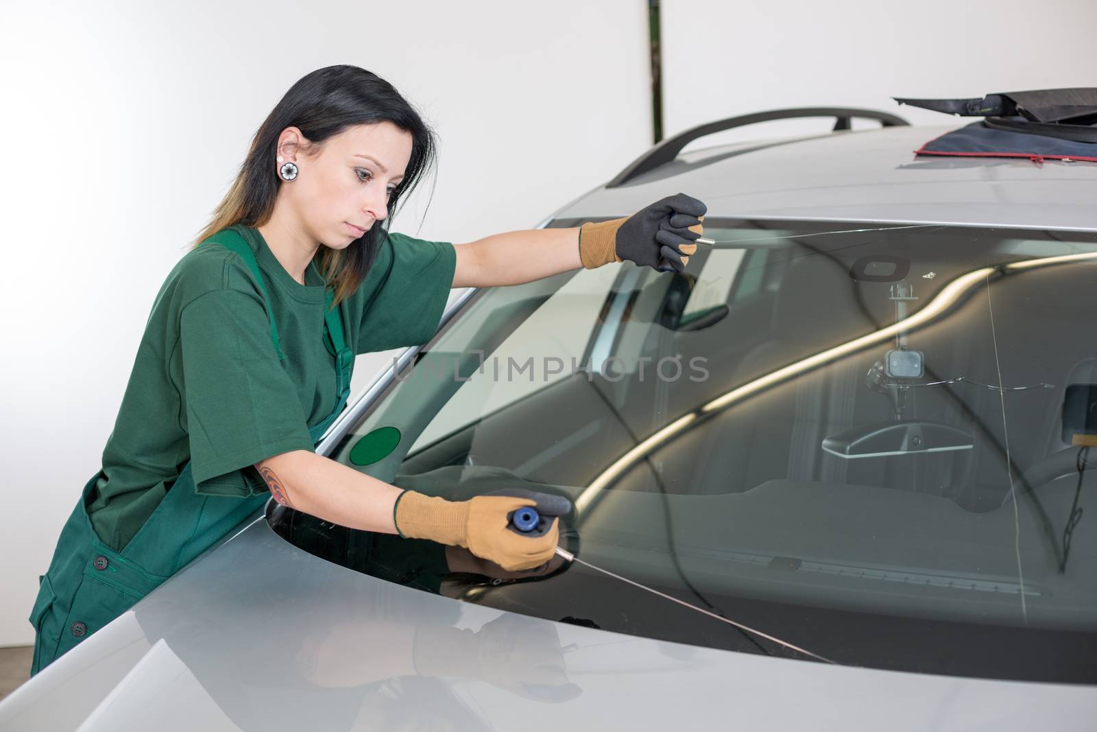Glazier cutting adhesive of windscreen with a wire to replace windshield