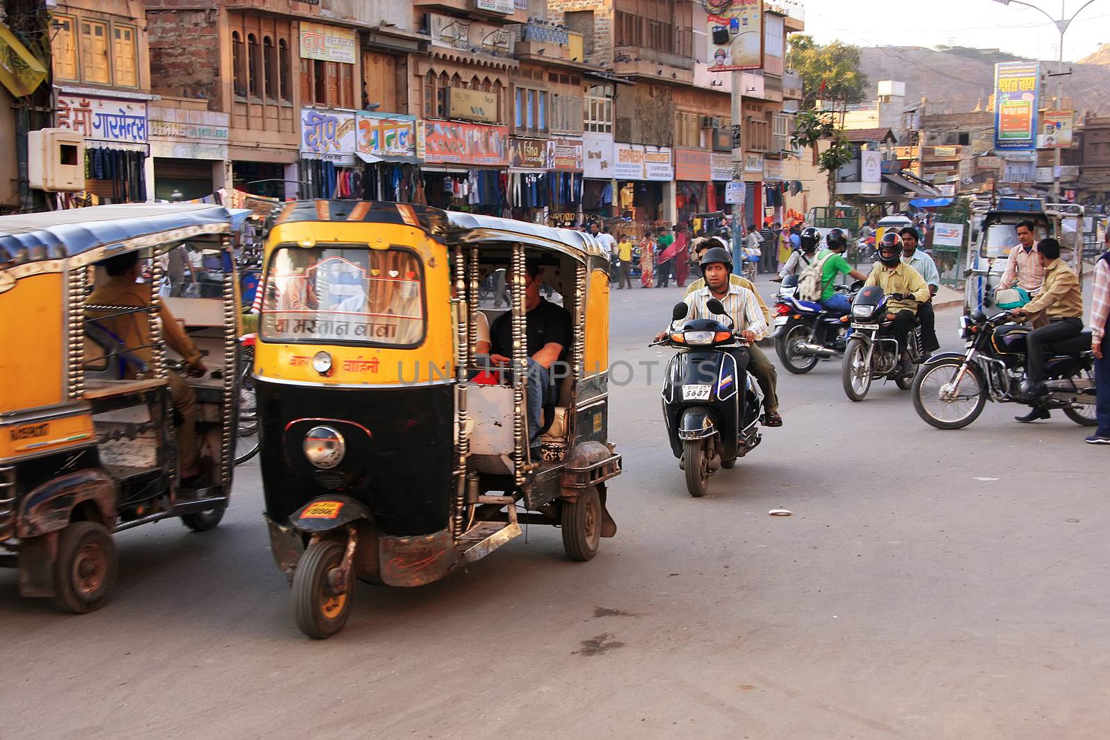 People riding tuk-tuks and motobikes at Sadar Market, Jodhpur, I by donya_nedomam