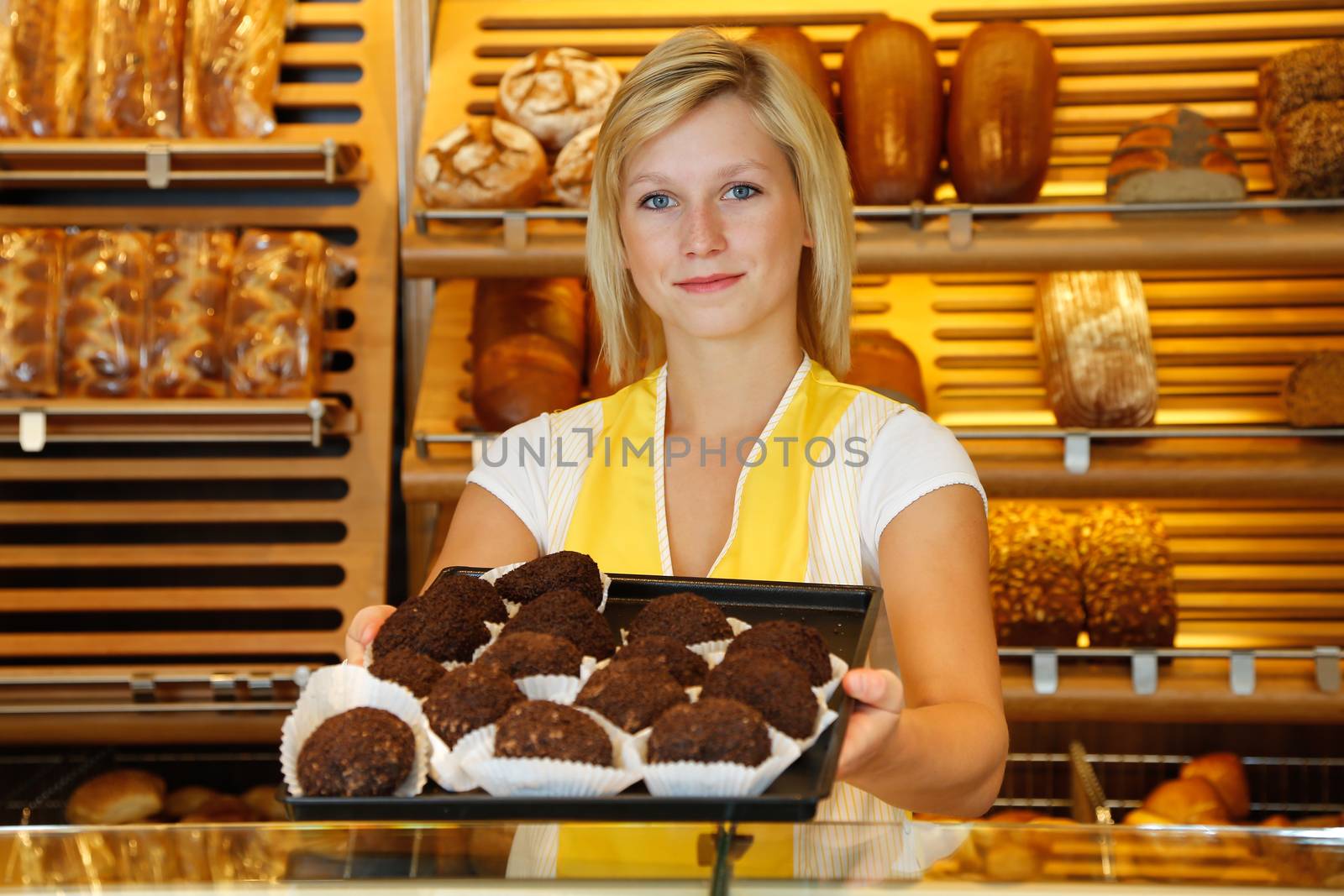 Shopkeeper in bakery presents tablet of rum balls by ikonoklast_fotografie