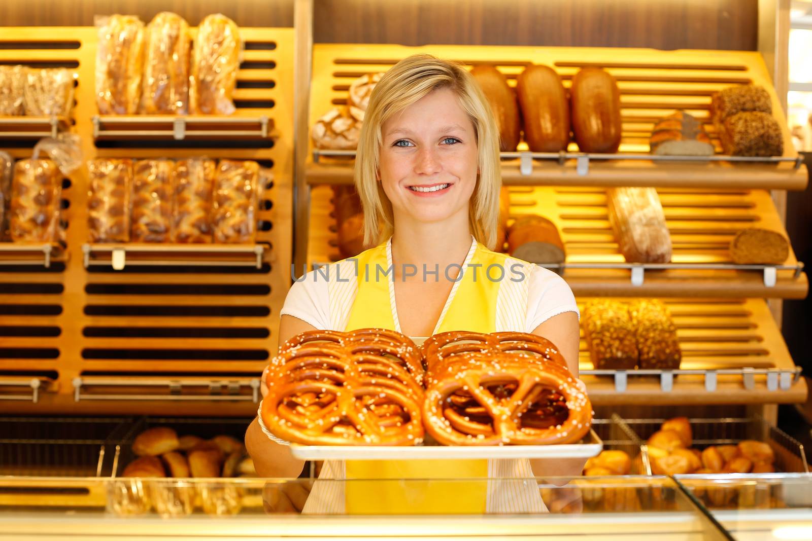 Shopkeeper in bakery with tablet of pretzels by ikonoklast_fotografie