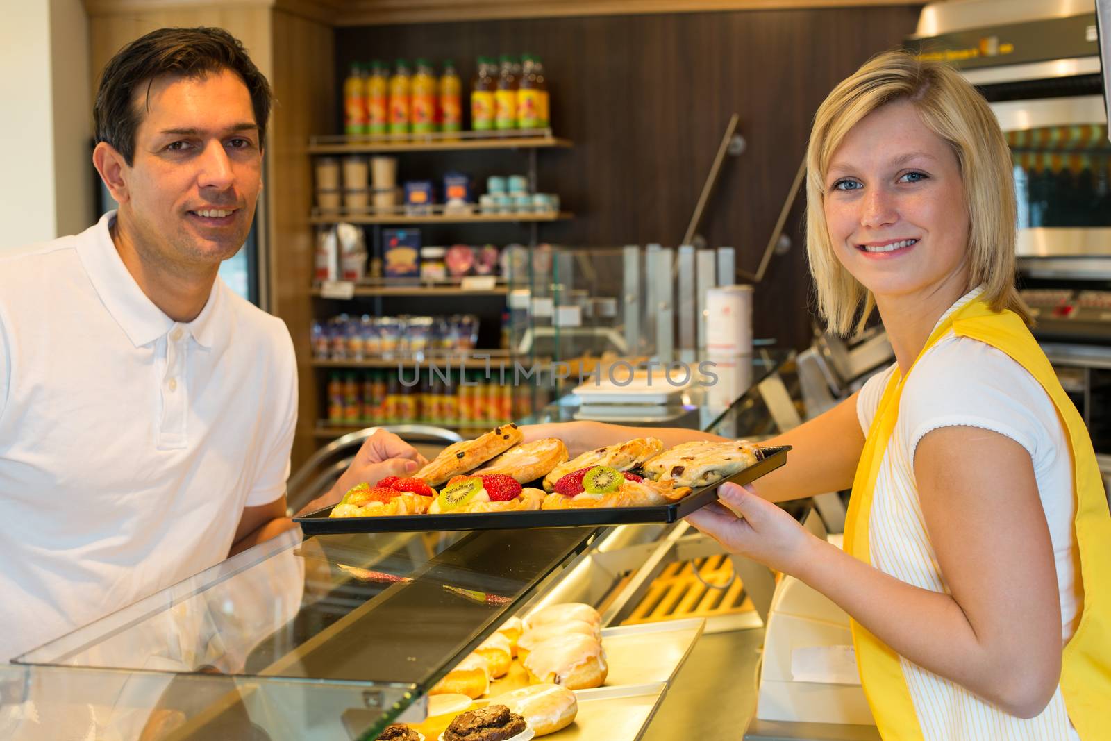 Shopkeeper giving pastry to customer by ikonoklast_fotografie