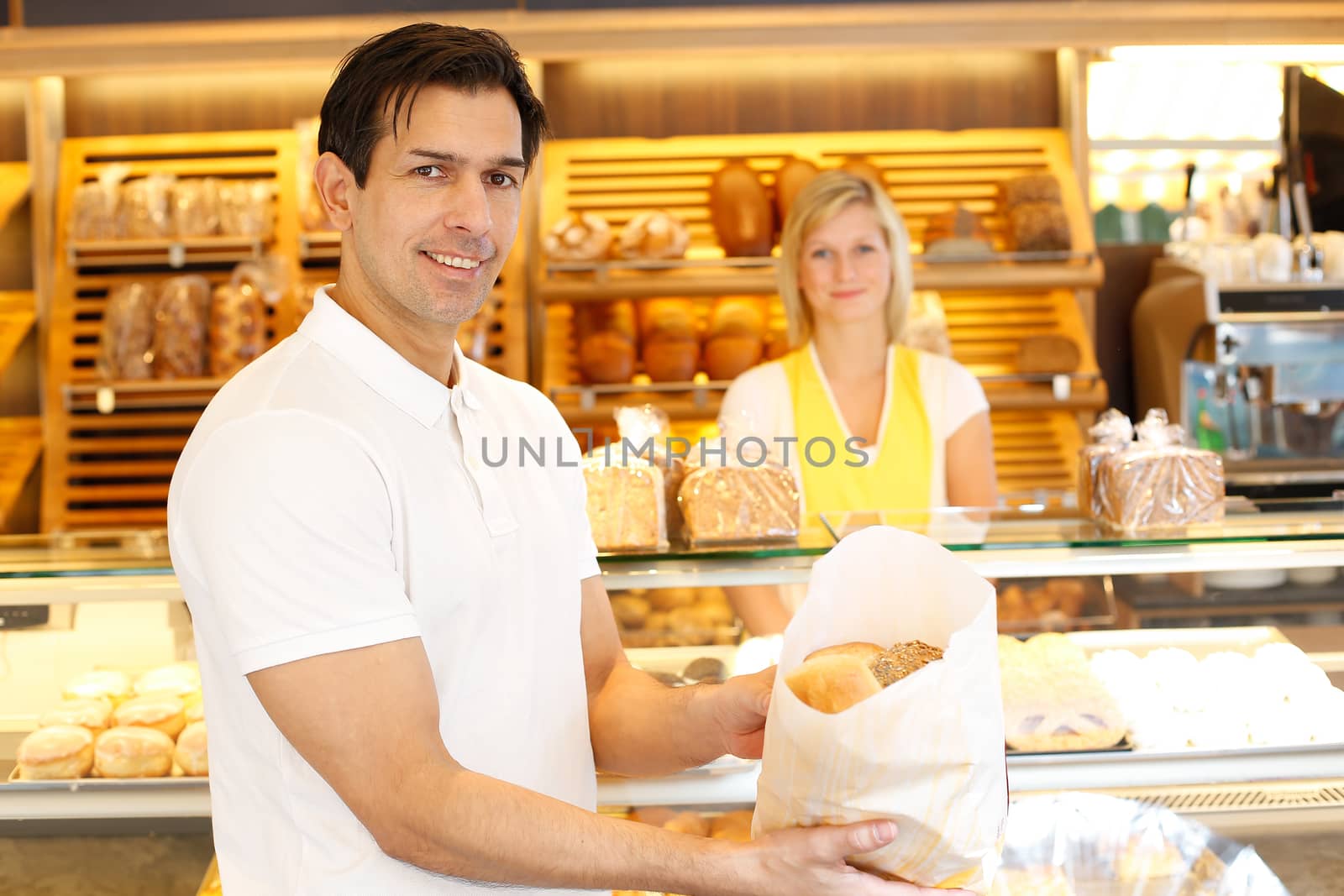 Happy customer in bakery with bags of bread by ikonoklast_fotografie