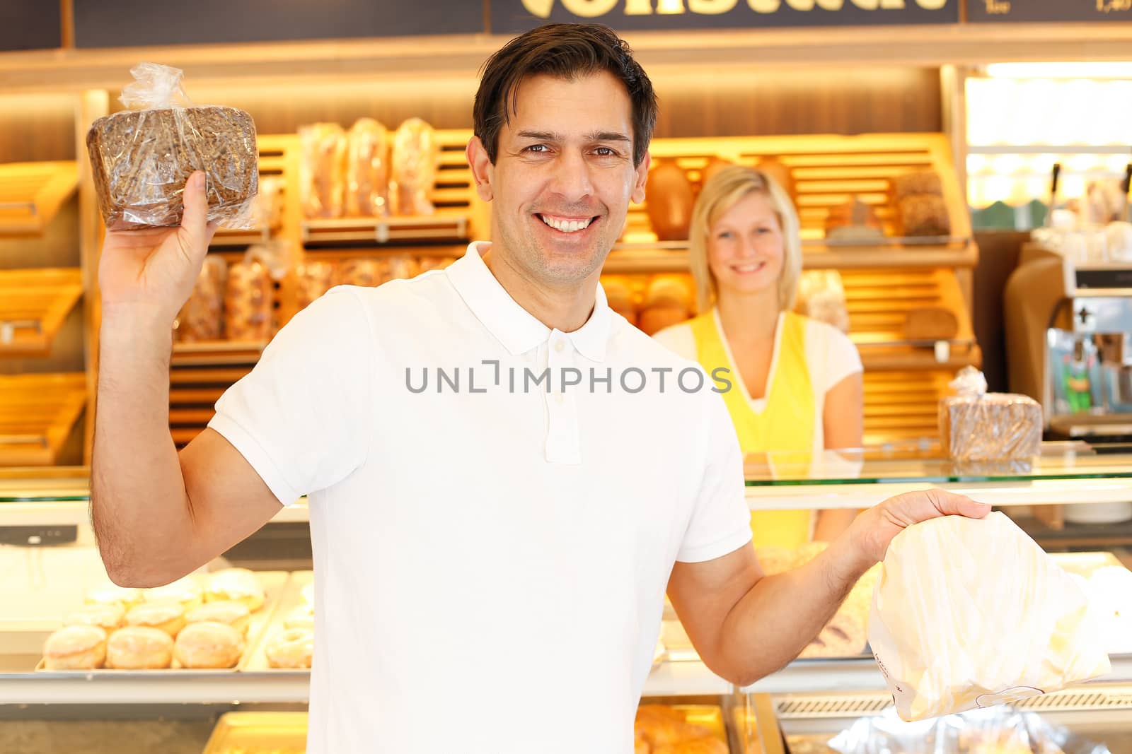 Happy customer in bakery with bags of bread by ikonoklast_fotografie