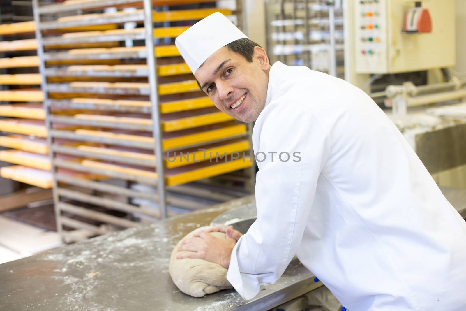 Baker kneading dough in a bakehouse or bakery