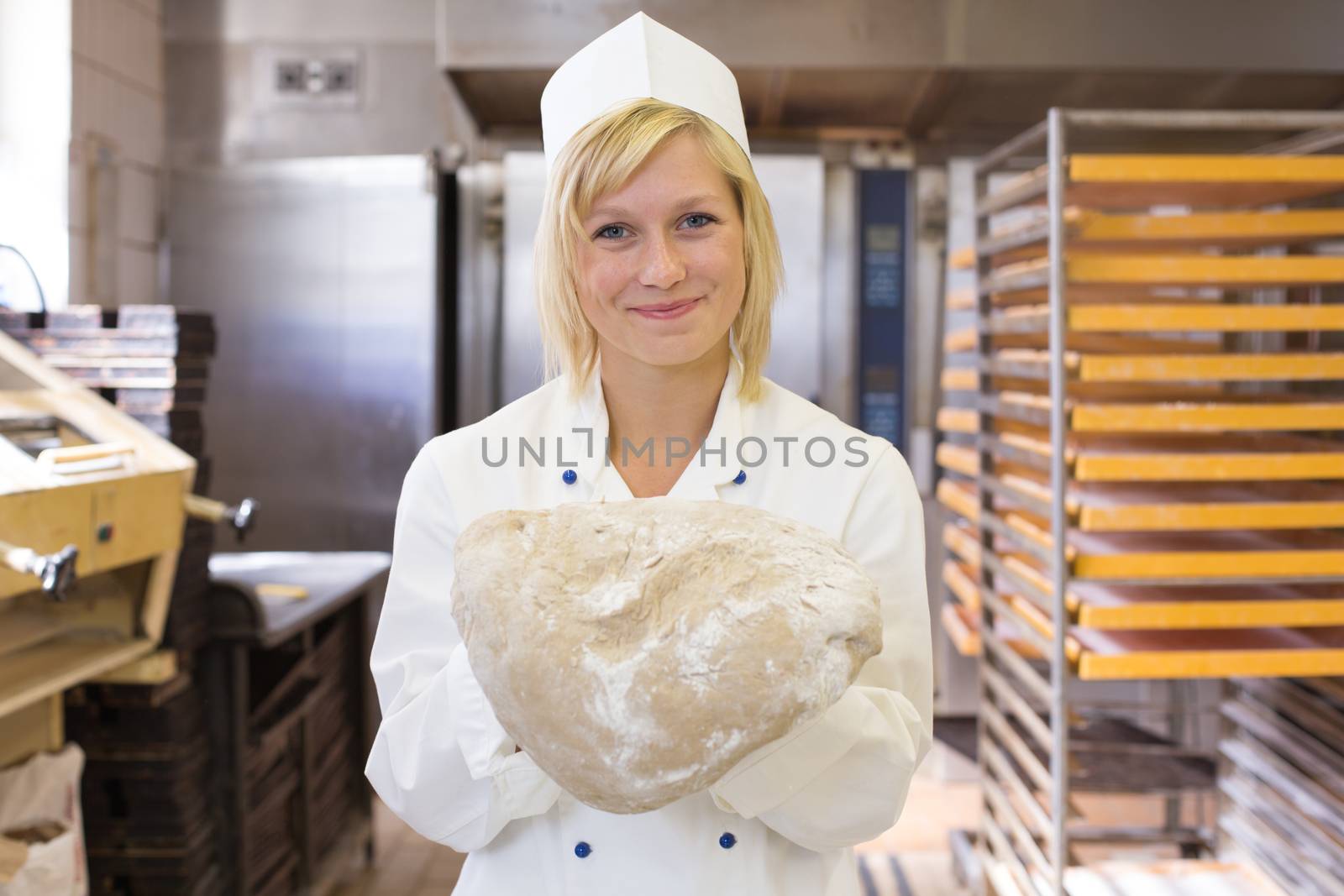 Baker with bread dough in bakery by ikonoklast_fotografie