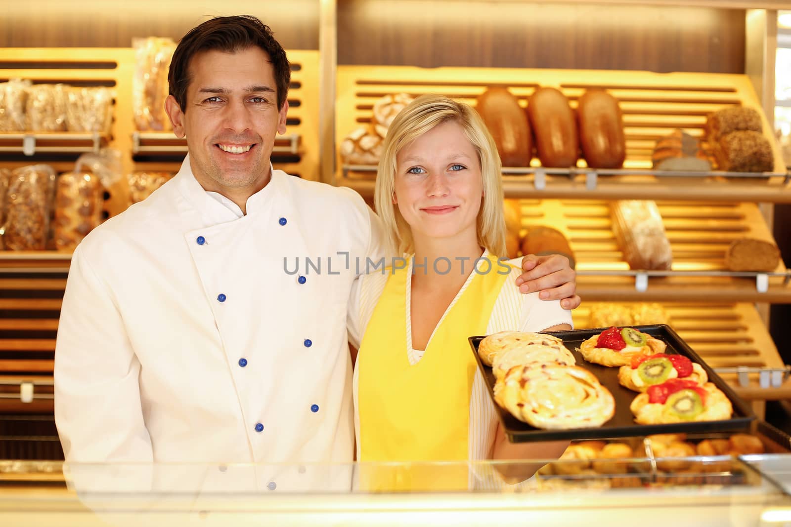 Baker and shopkeeper in bakery with tablet of cake by ikonoklast_fotografie