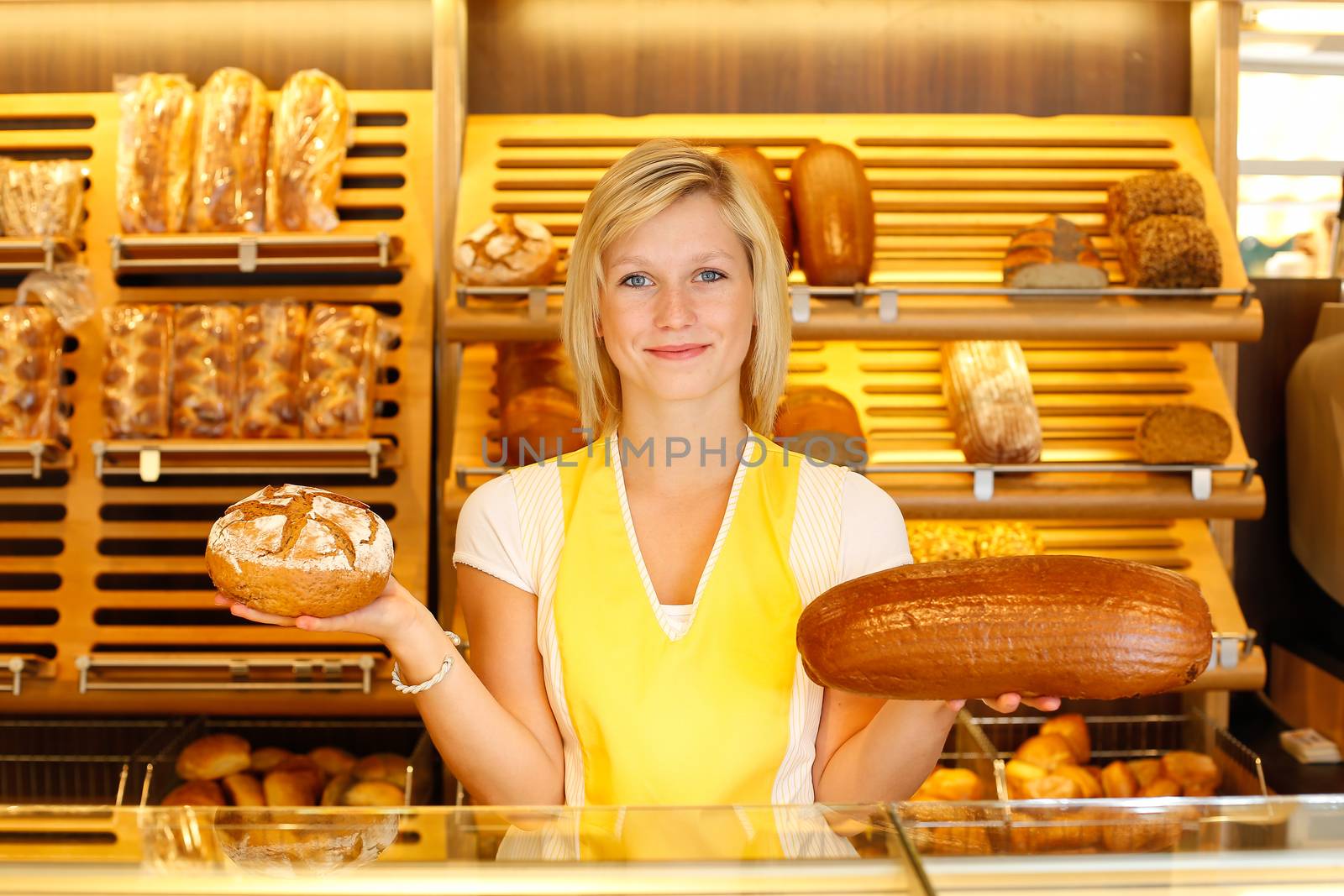 Shopkeeper in bakery with two loafs of bread