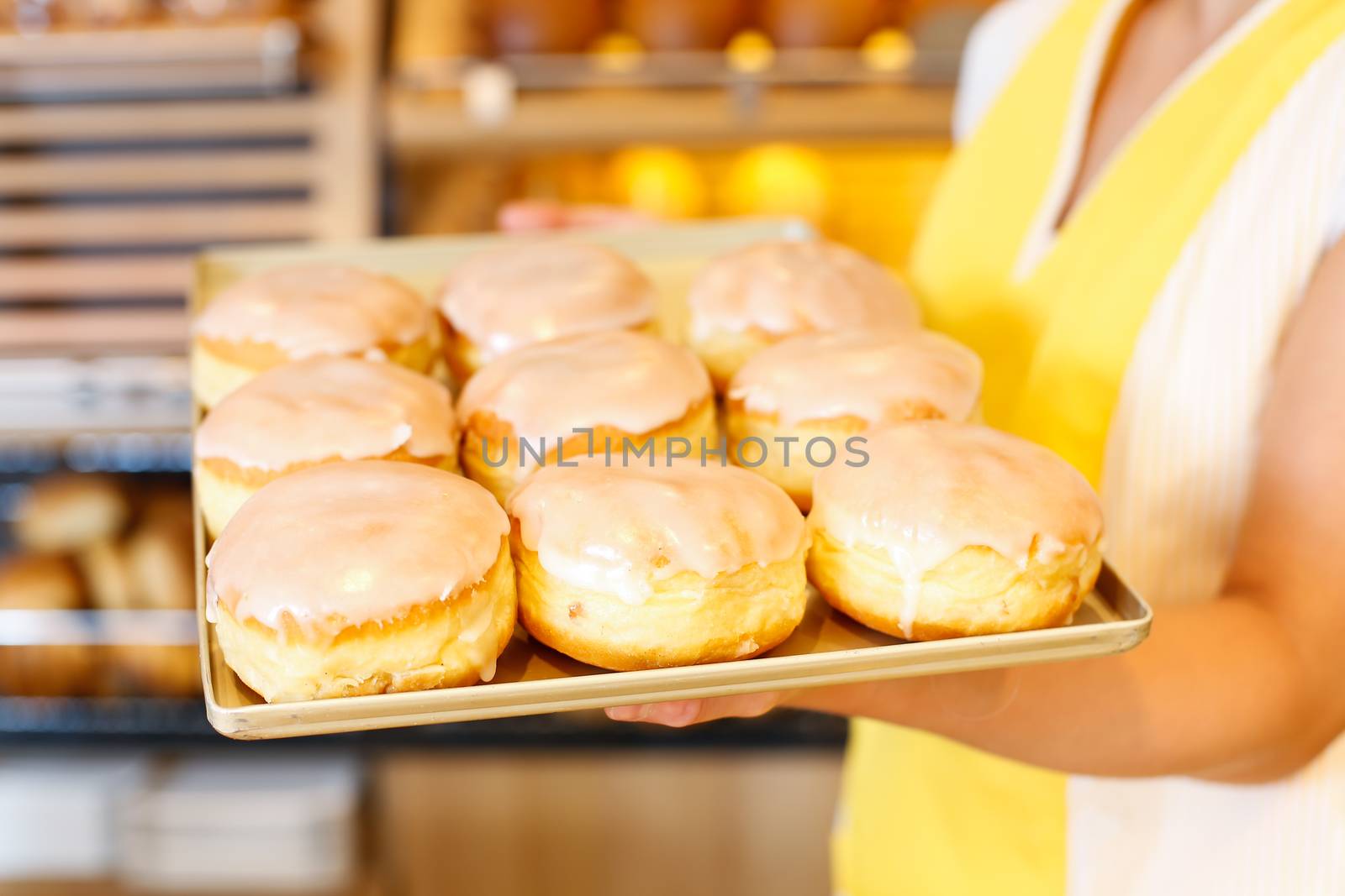 Bakery shopkeeper with a tablet full of doughnuts or Berliners