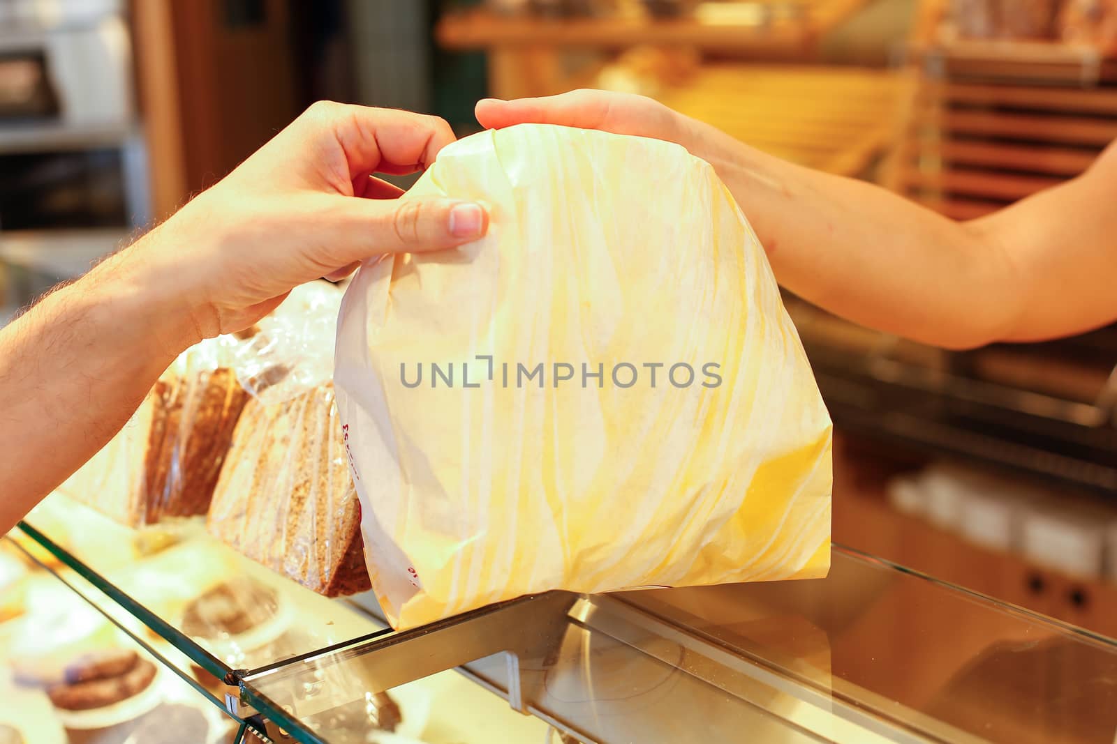 Baker's shop shopkeeper gives bread to customer by ikonoklast_fotografie