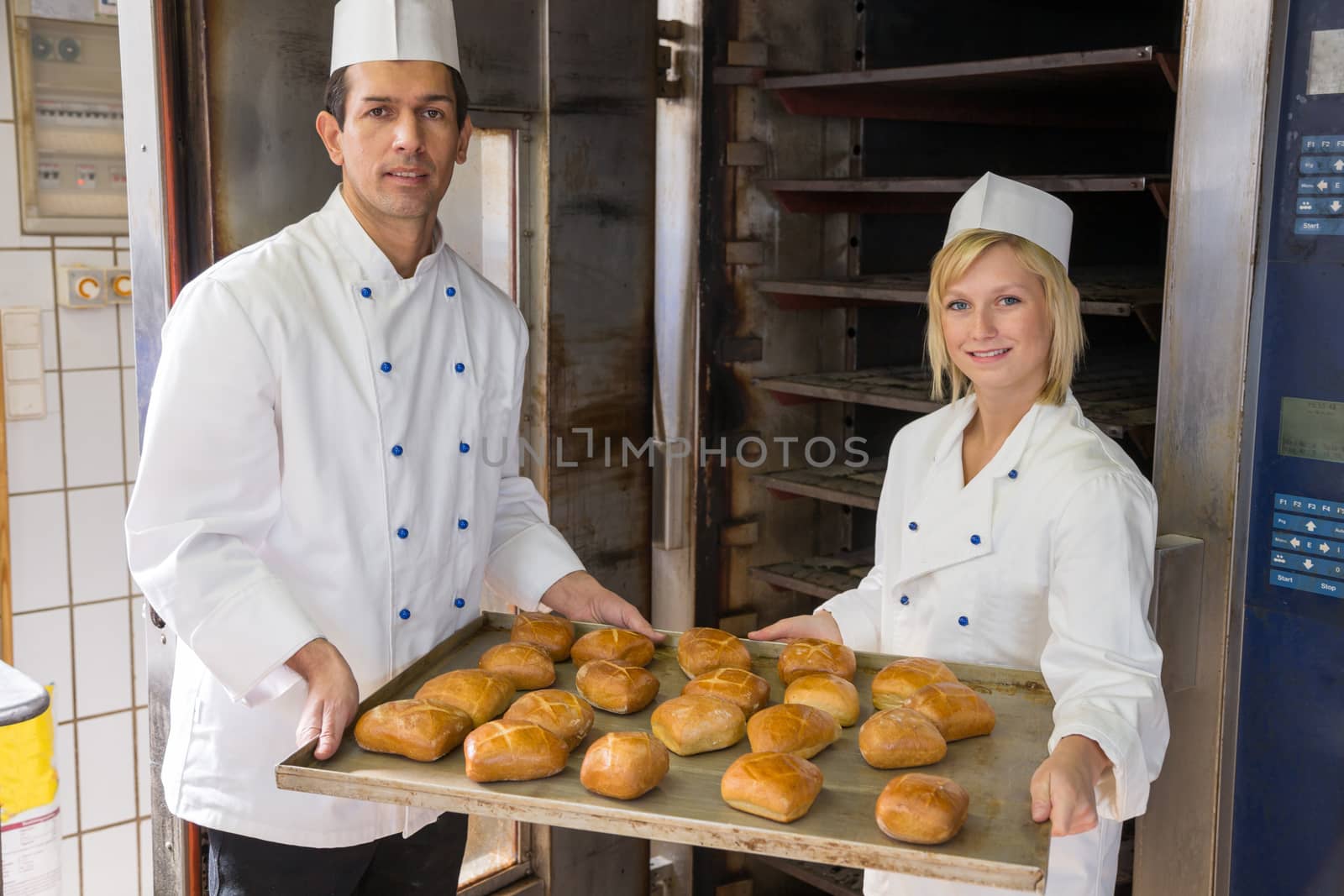 Two bakers with tablet of buns in a bakery