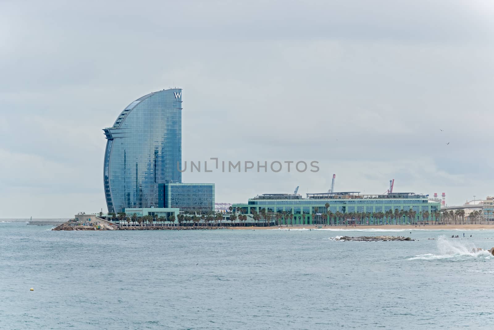 Barcelona, Spain - January 25, 2014: View at the Port and W Barcelona, popularly known as the Hotel Vela (Sail Hotel) due to its shape.It  is a building designed by Ricardo Bofill is located in the Barceloneta district of Barcelona, in the expansion of the Port of Barcelona. 