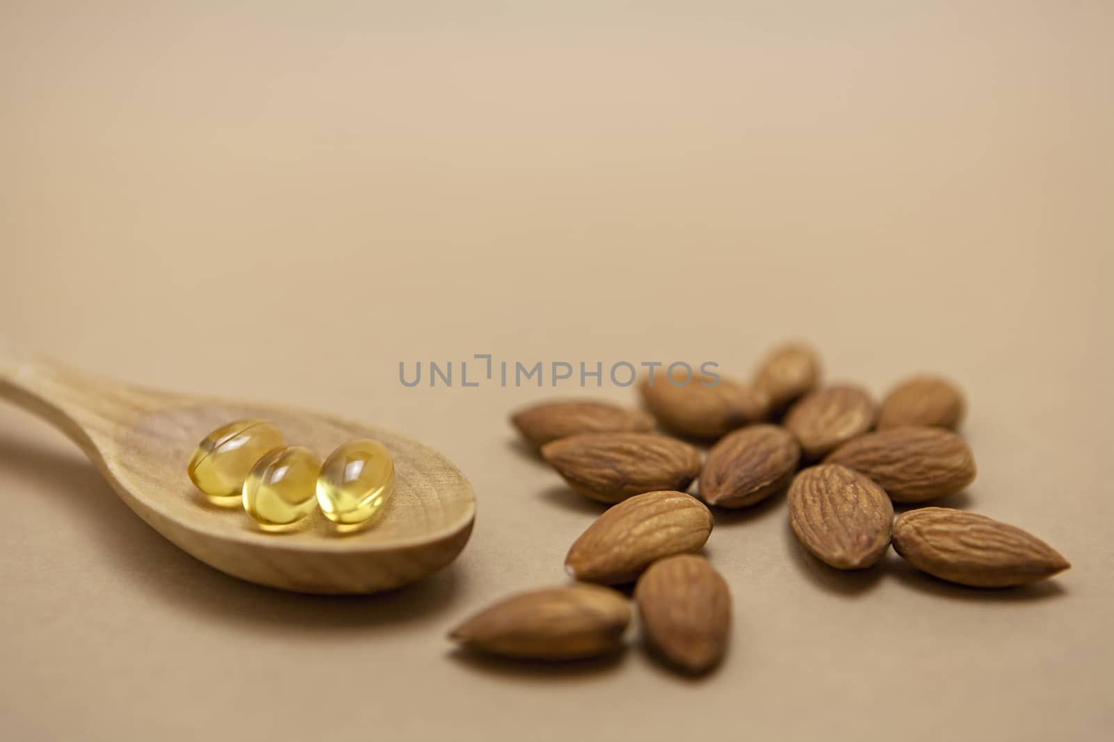 Almond oil in capsules isolated on brown background by digicomphoto