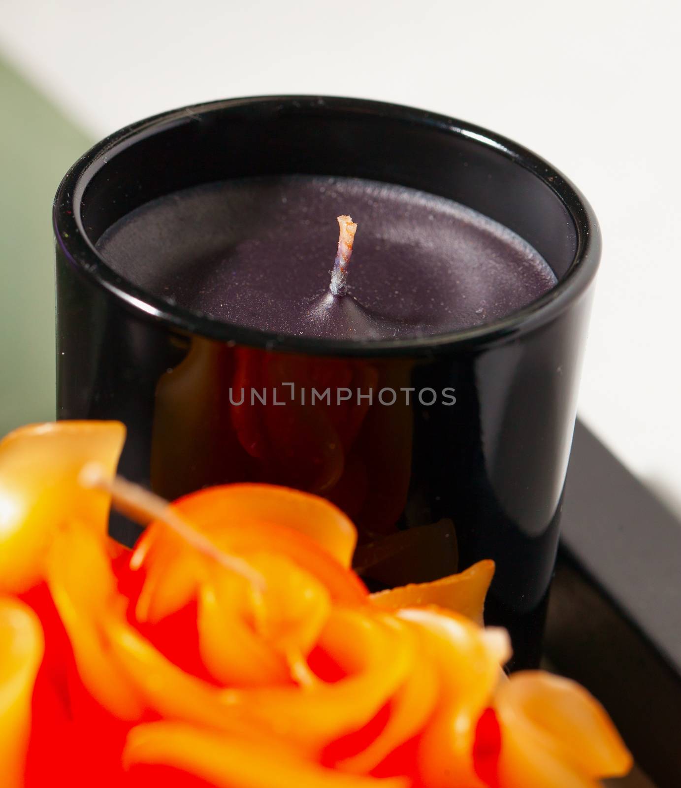 Black candle near a rose decoration, white background