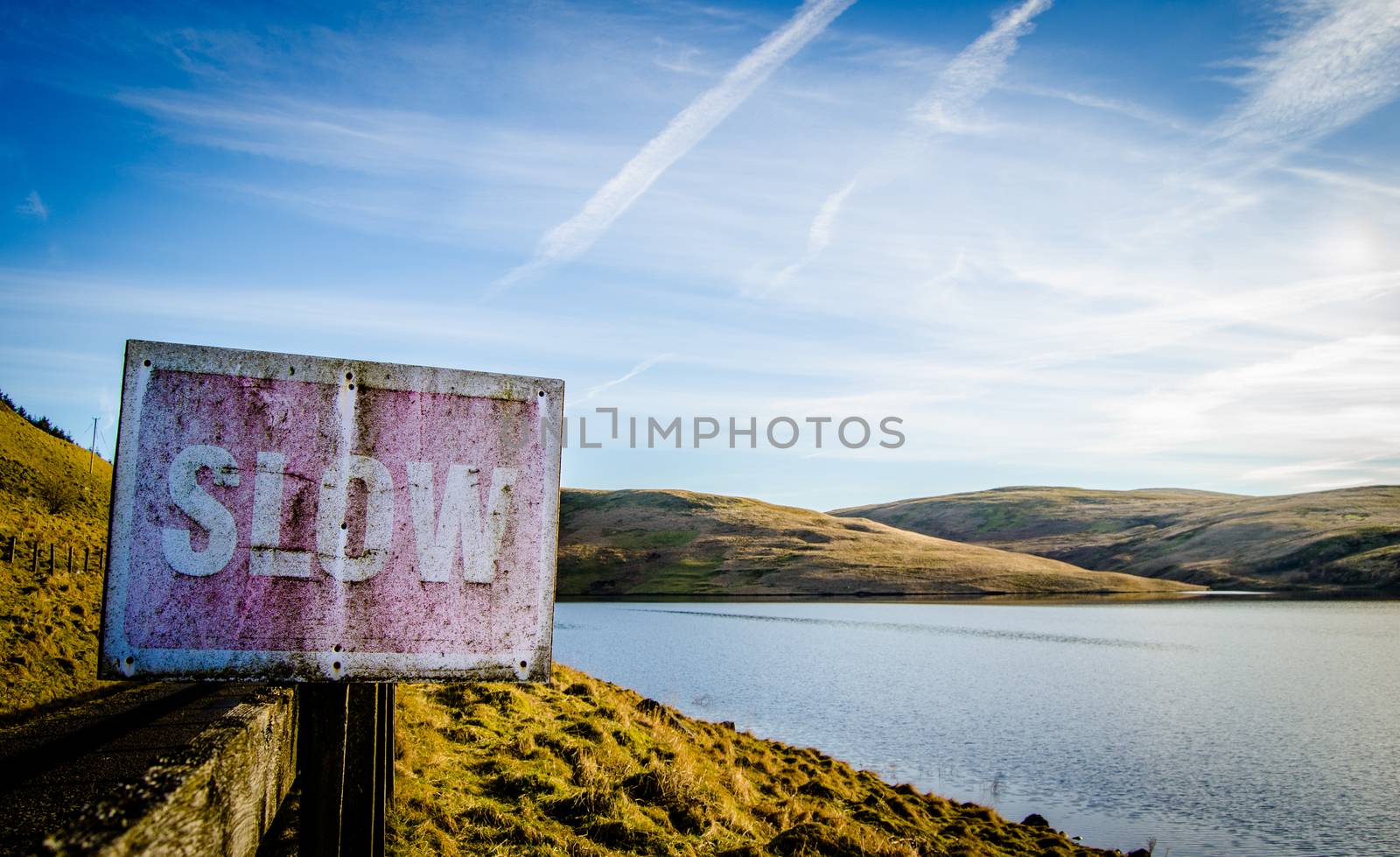 Conceptual Image Of Rustic Slow Sign Beside Tranquil Scenic Lake