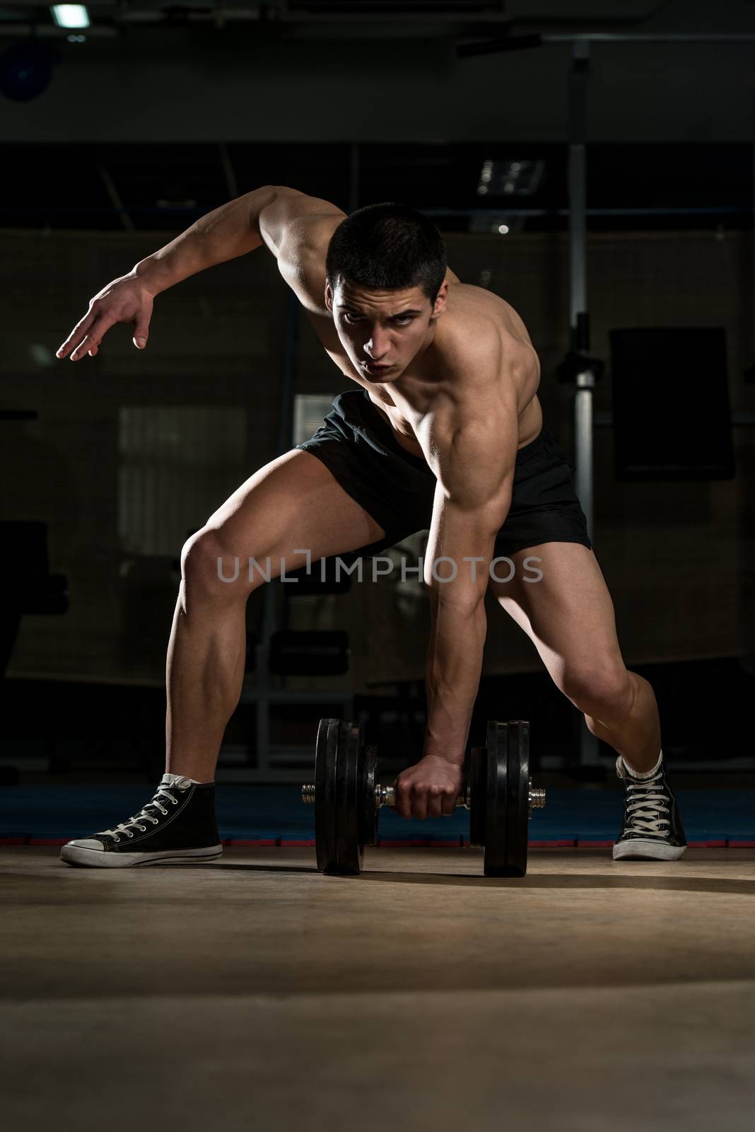 Young Body Builder Lifting Heavy Dumbbell by JalePhoto