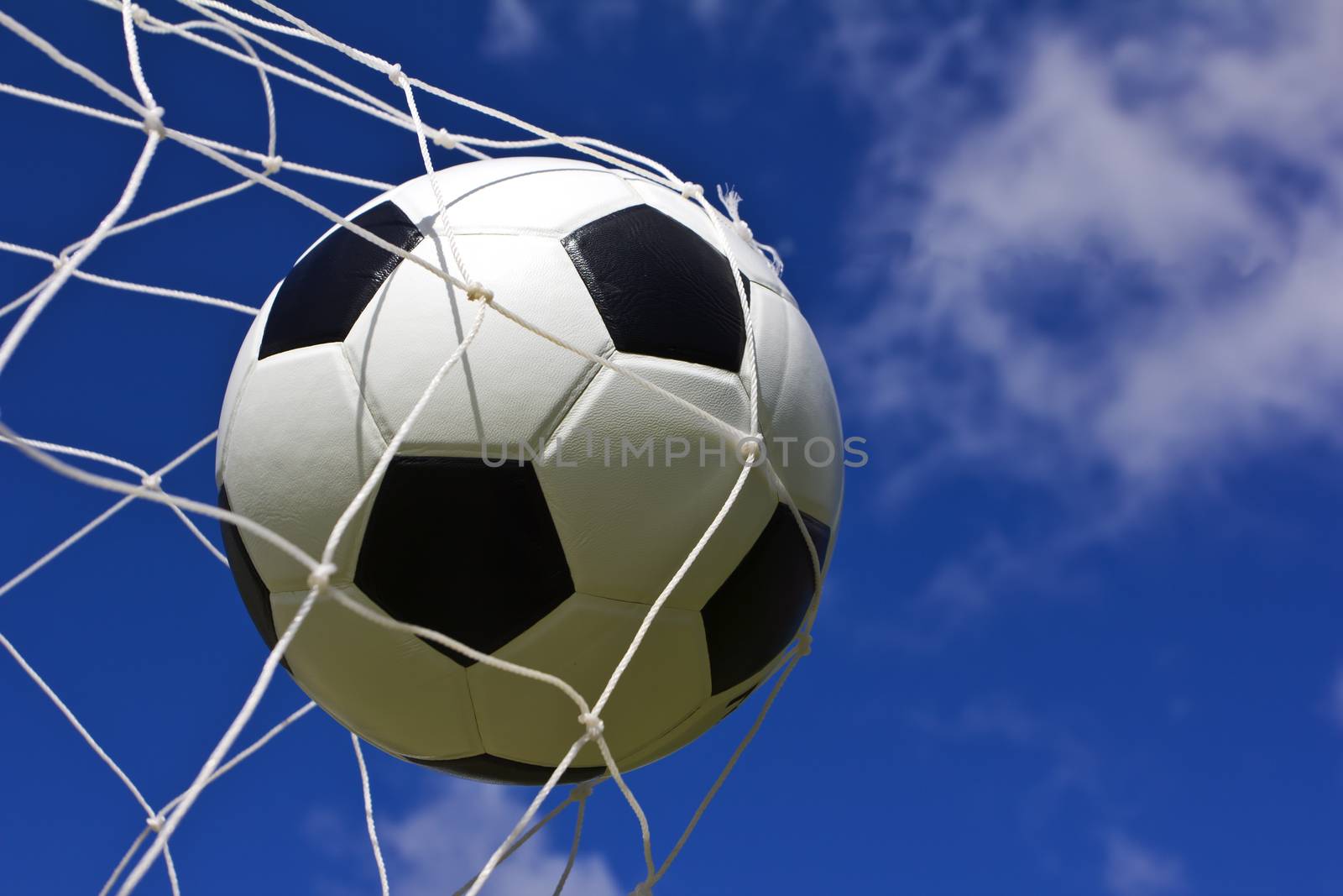 Soccer ball in net on blue sky